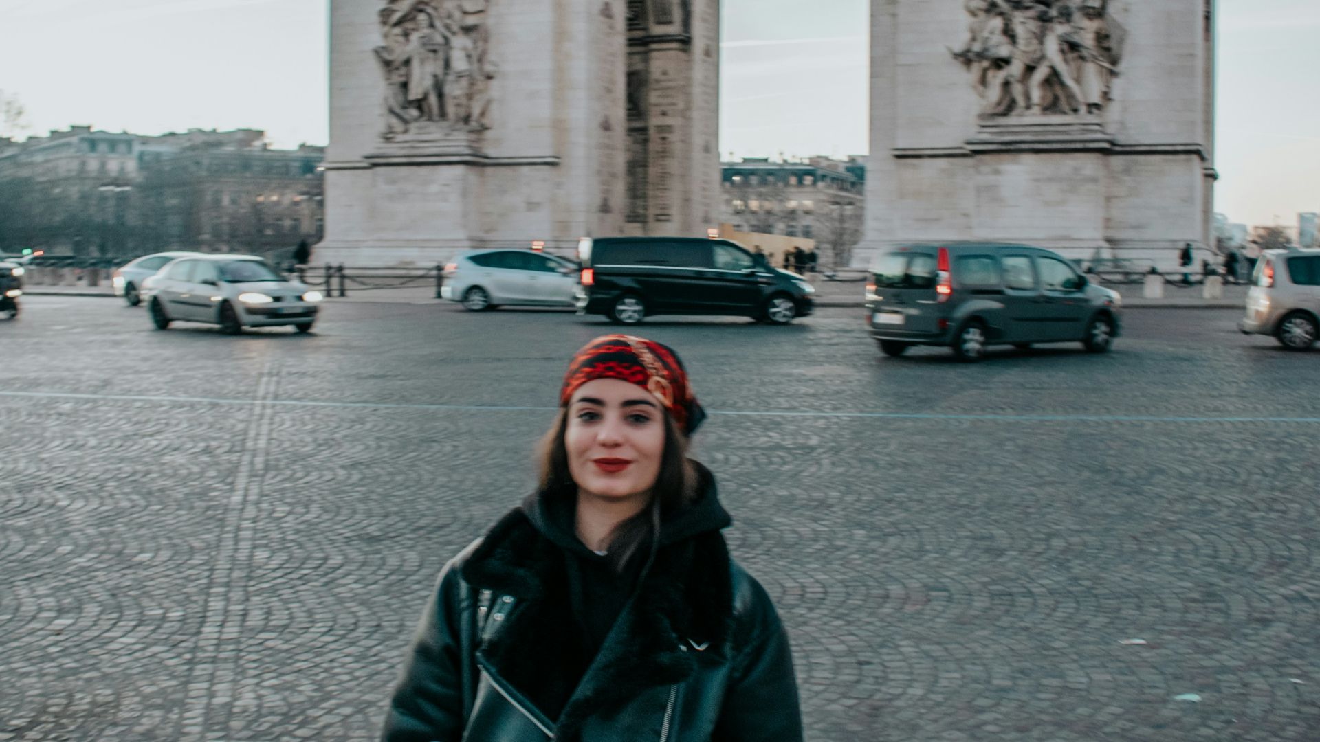 a woman standing in front of the arc of triumph