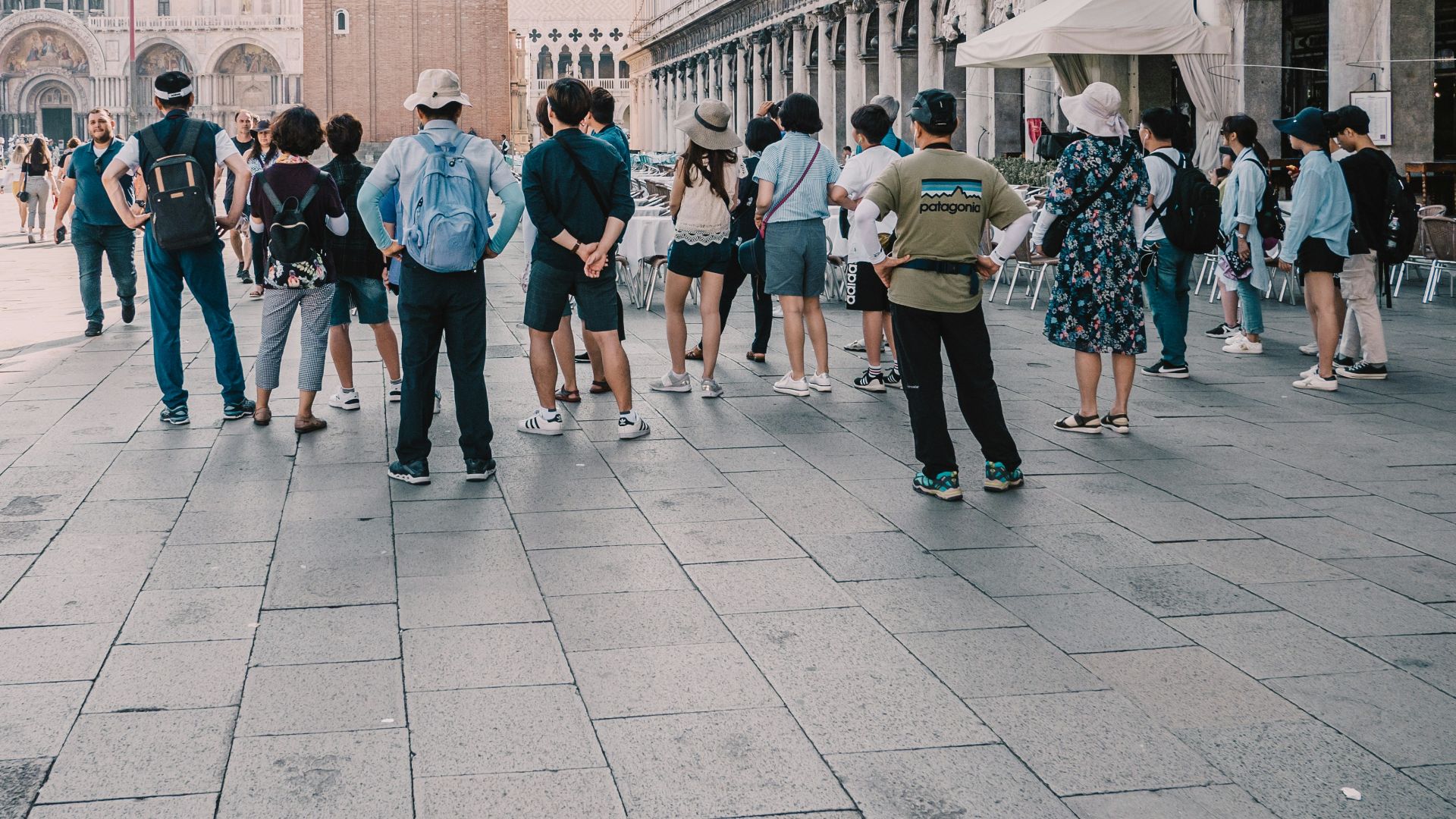 a group of people standing on a street next to a tall building