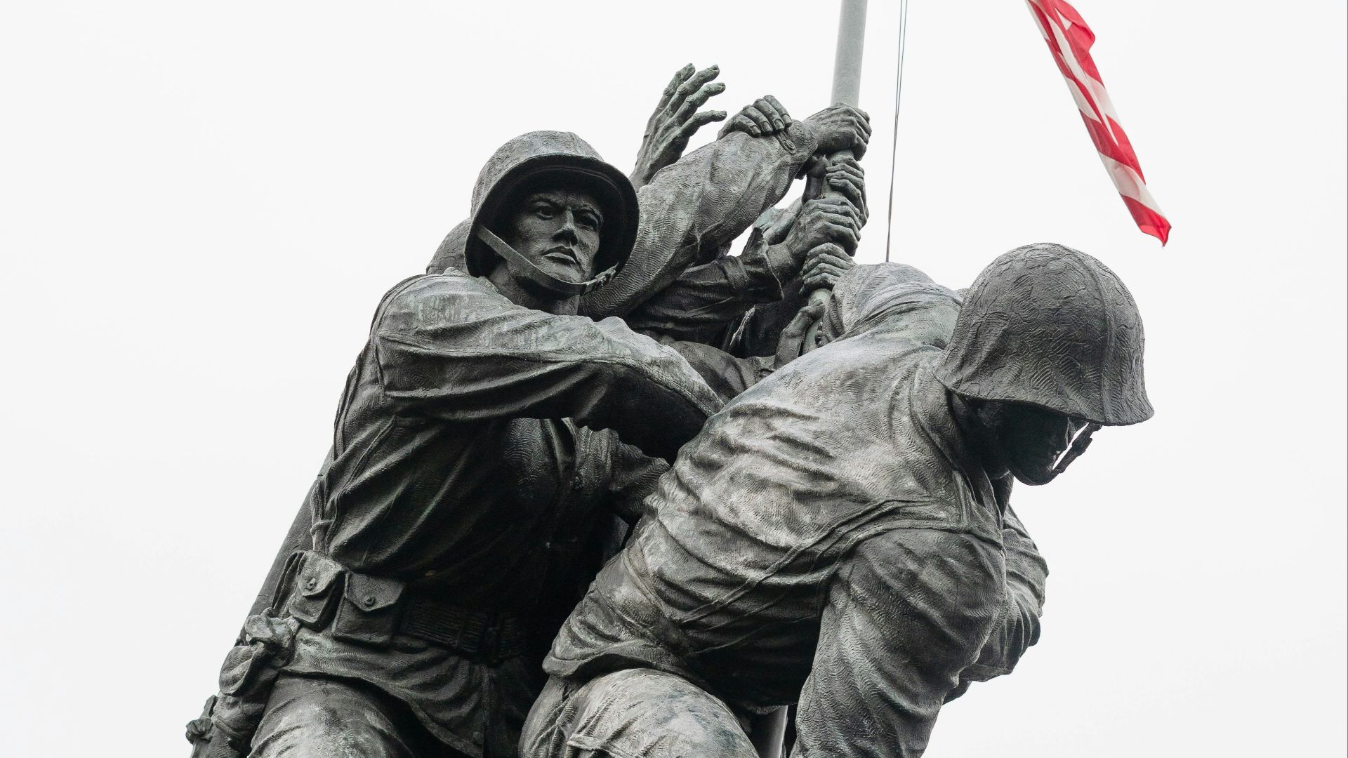 A statue of soldiers holding a flag on top of a hill