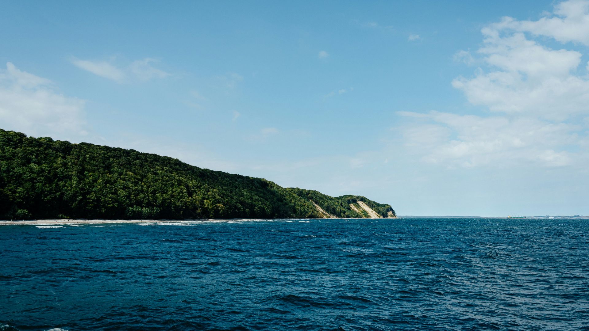 green mountain beside blue sea under blue sky during daytime