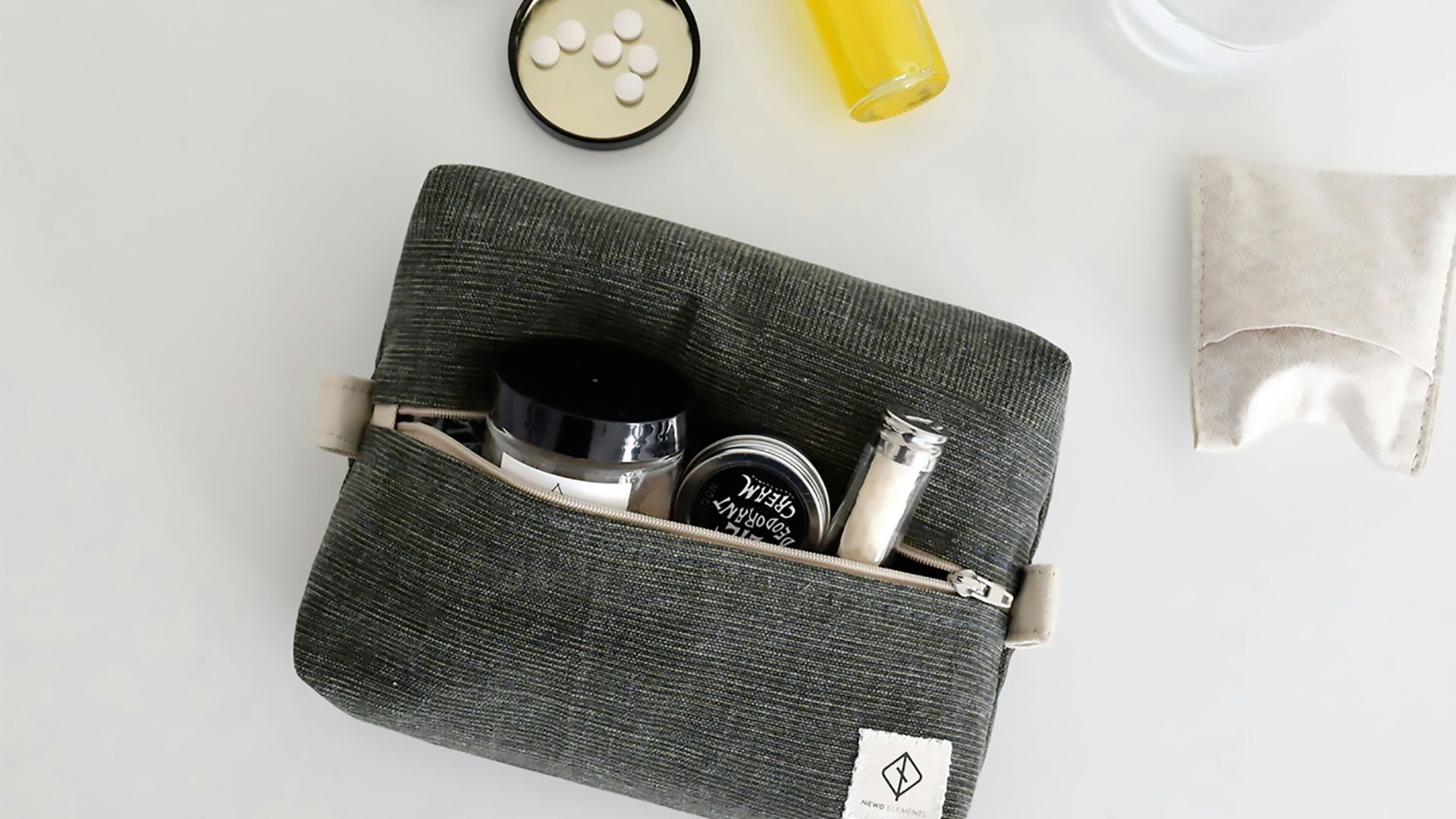 Gray toiletry bag with travel-sized cosmetics and full-sized products.