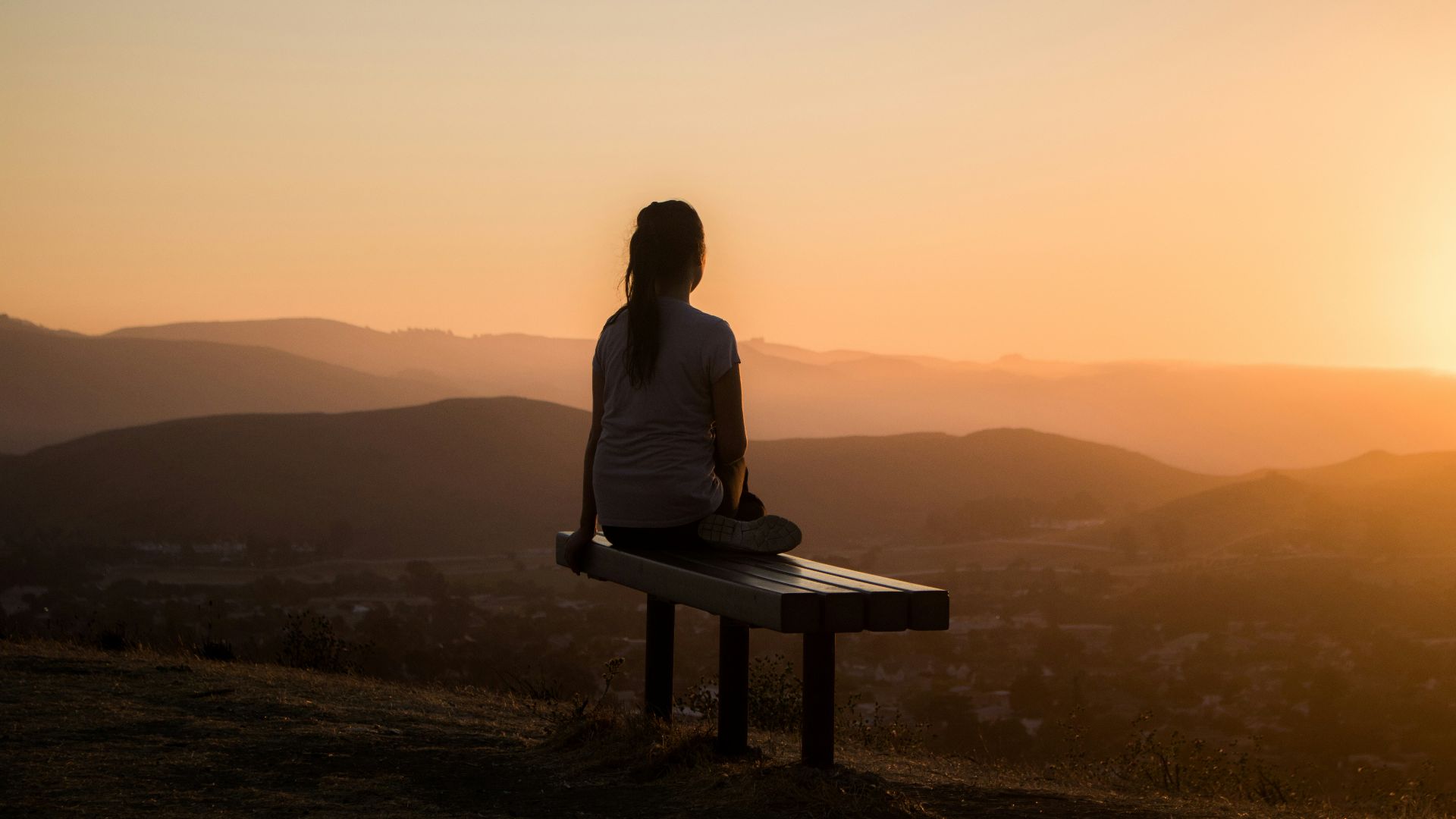 woman sitting on bench over viewing mountain