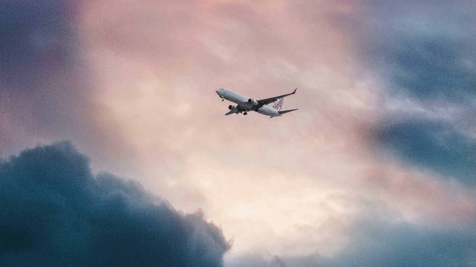 white plane flying over gray clouds
