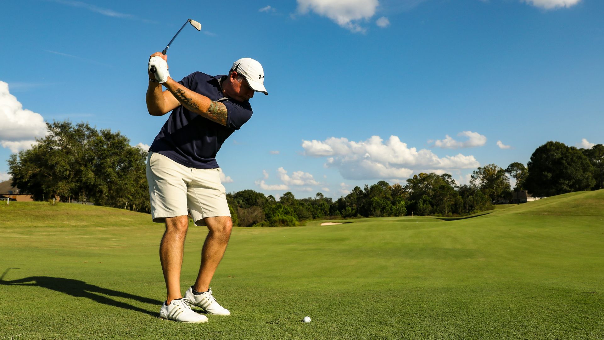 man in black shirt and white shorts playing golf during daytime