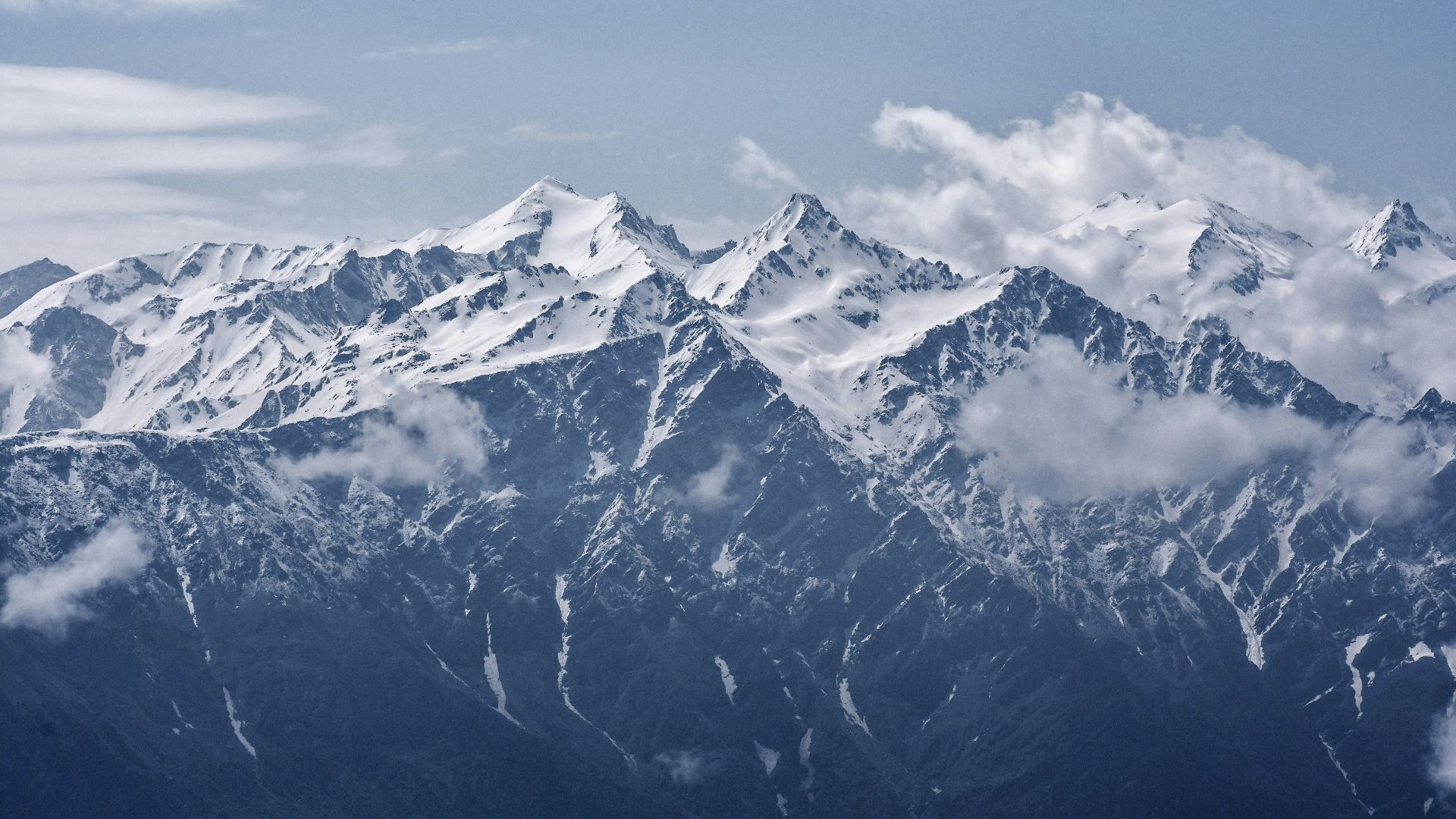 snow-covered mountains with white clouds during daytime