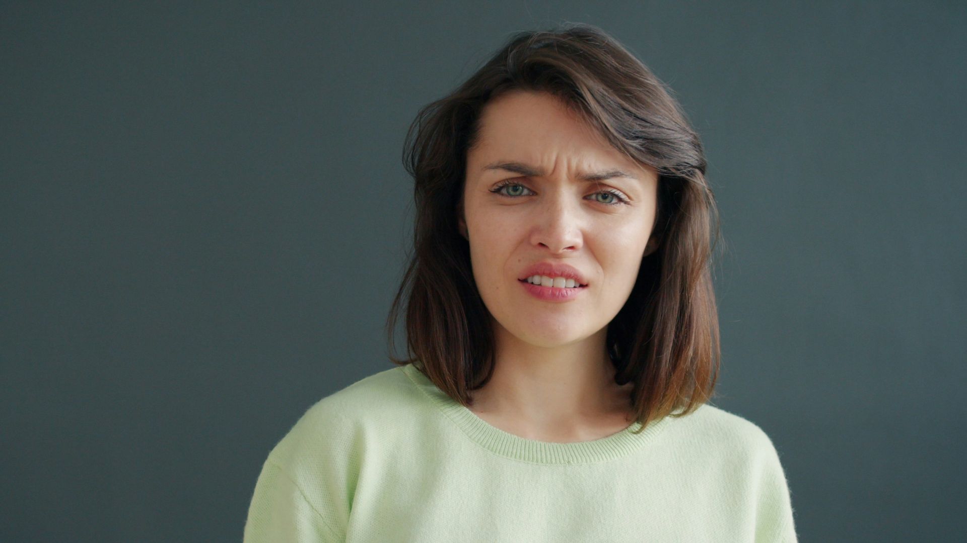 Woman with a disgusted expression against a dark background