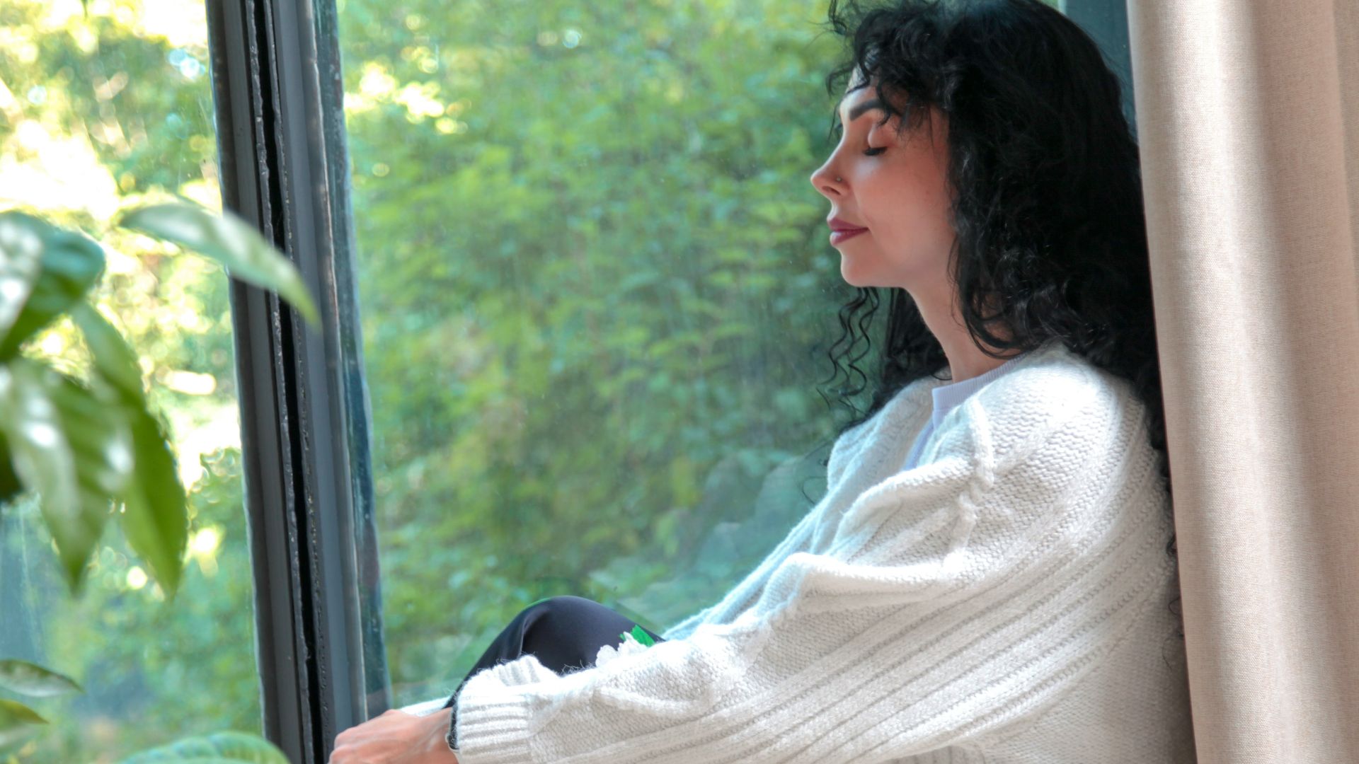 a woman sitting on a window sill looking out the window