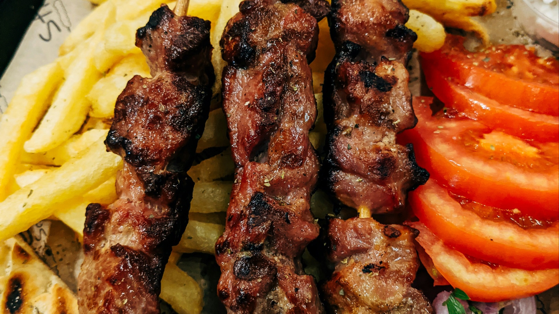 grilled meat with sliced tomato and green vegetable on white ceramic plate
