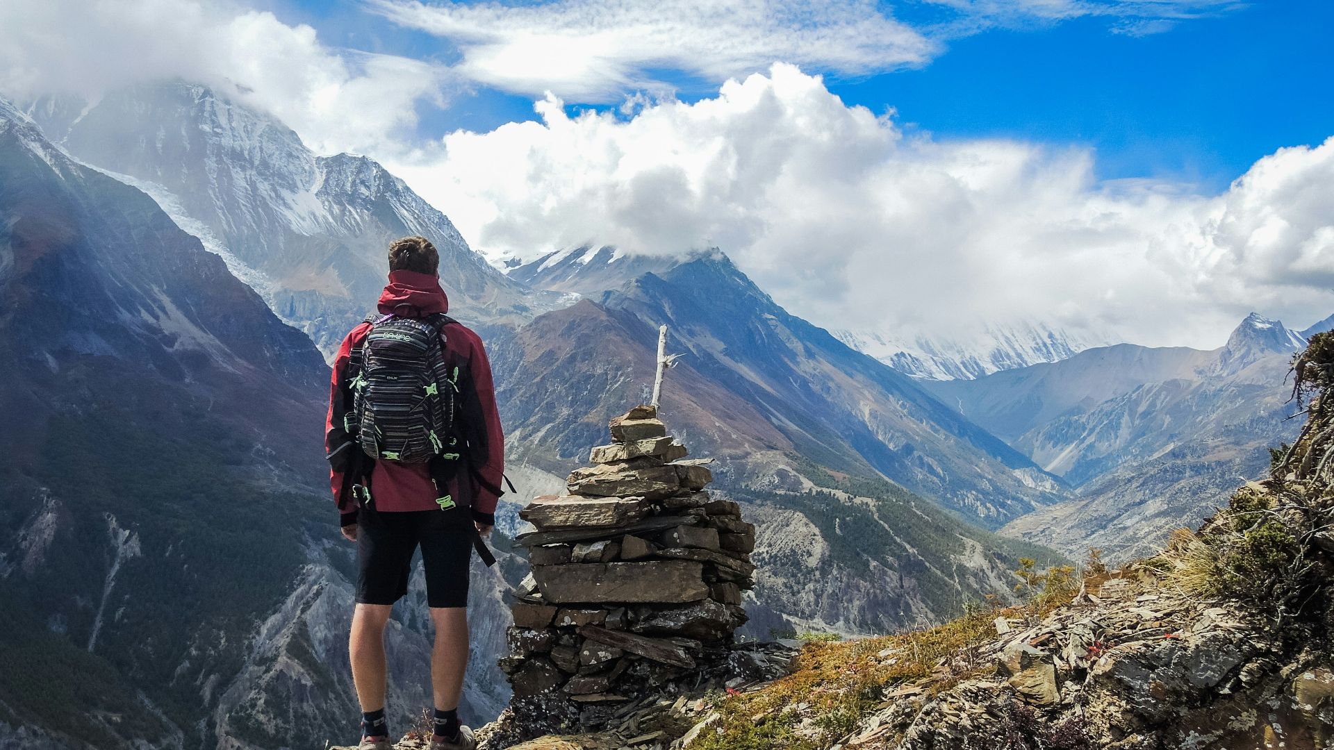 man standing on top of mountain beside cairn stones