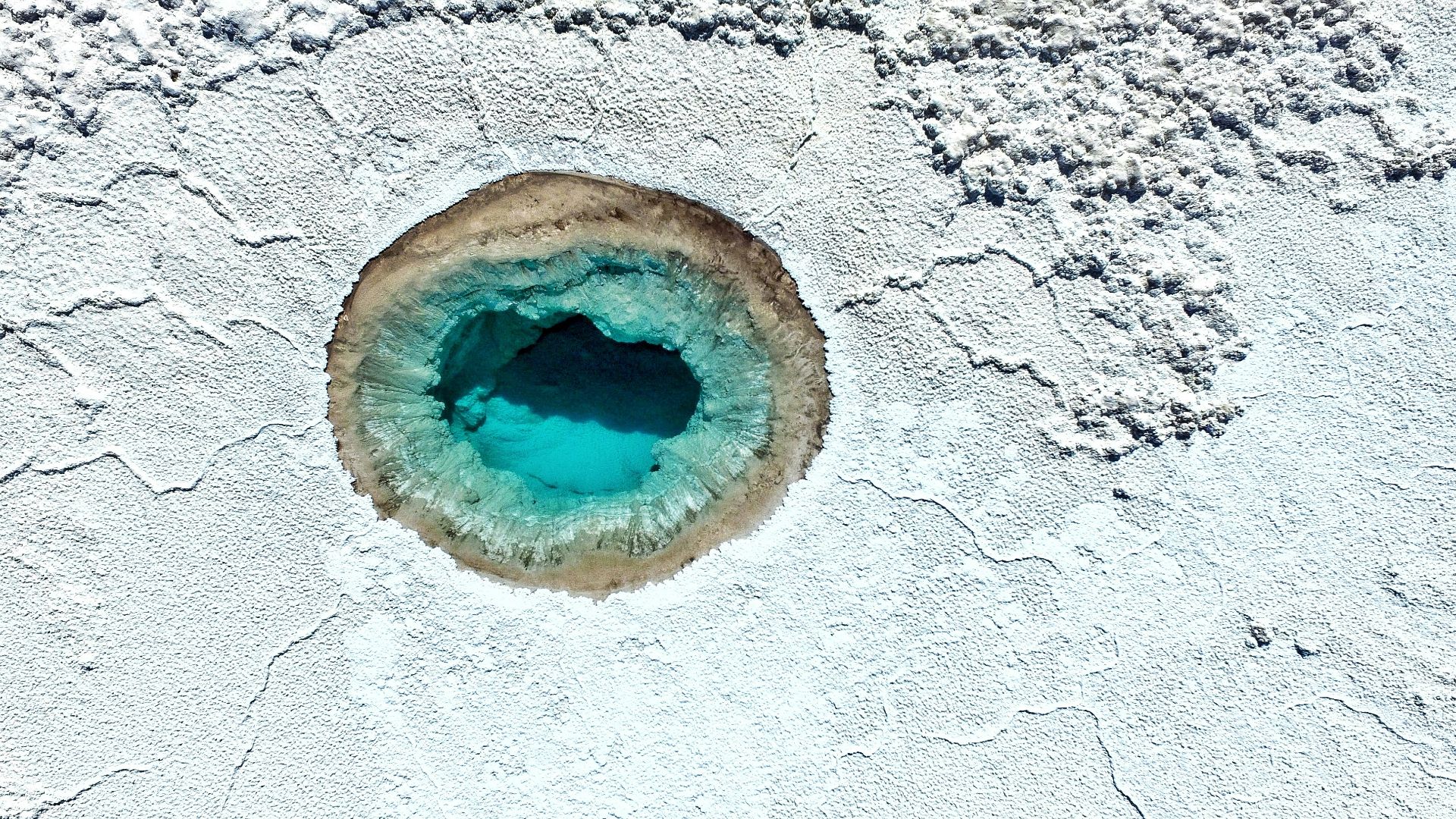 a blue hole in the white sand of a beach