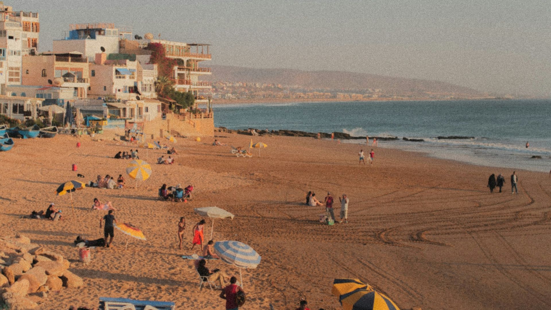 a group of people sitting on top of a sandy beach