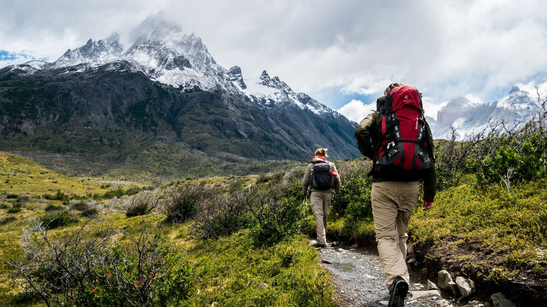 two person walking towards mountain covered with snow