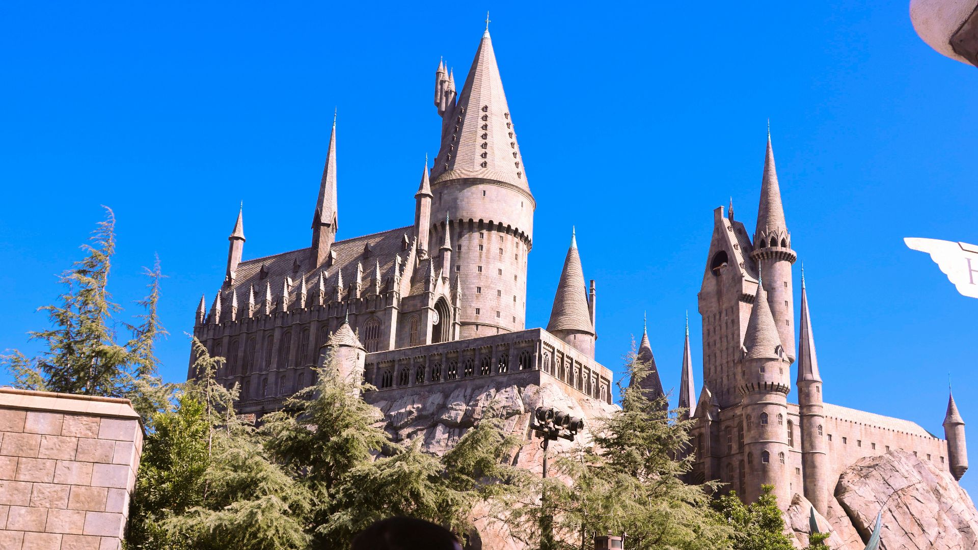 Hogwarts castle stands tall under a blue sky.