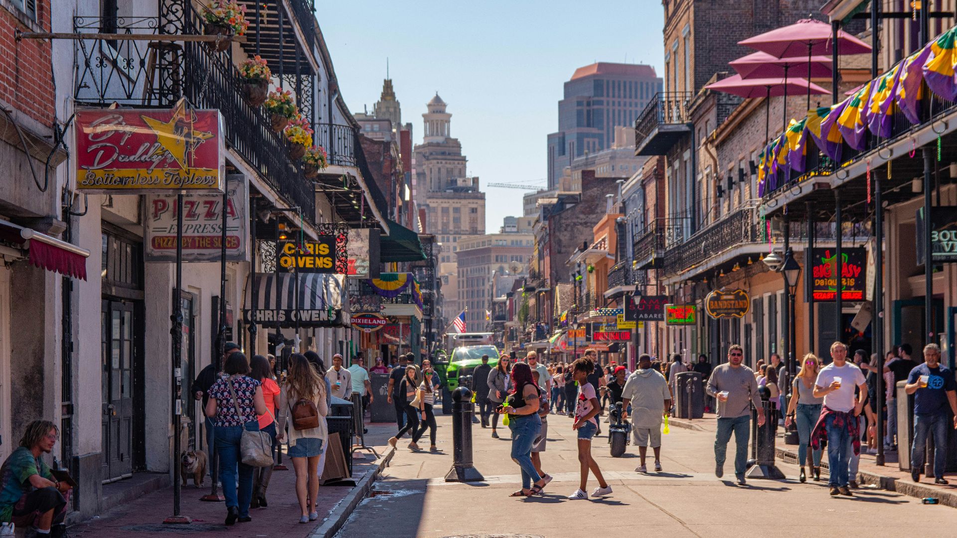 a group of people walking down a street next to tall buildings
