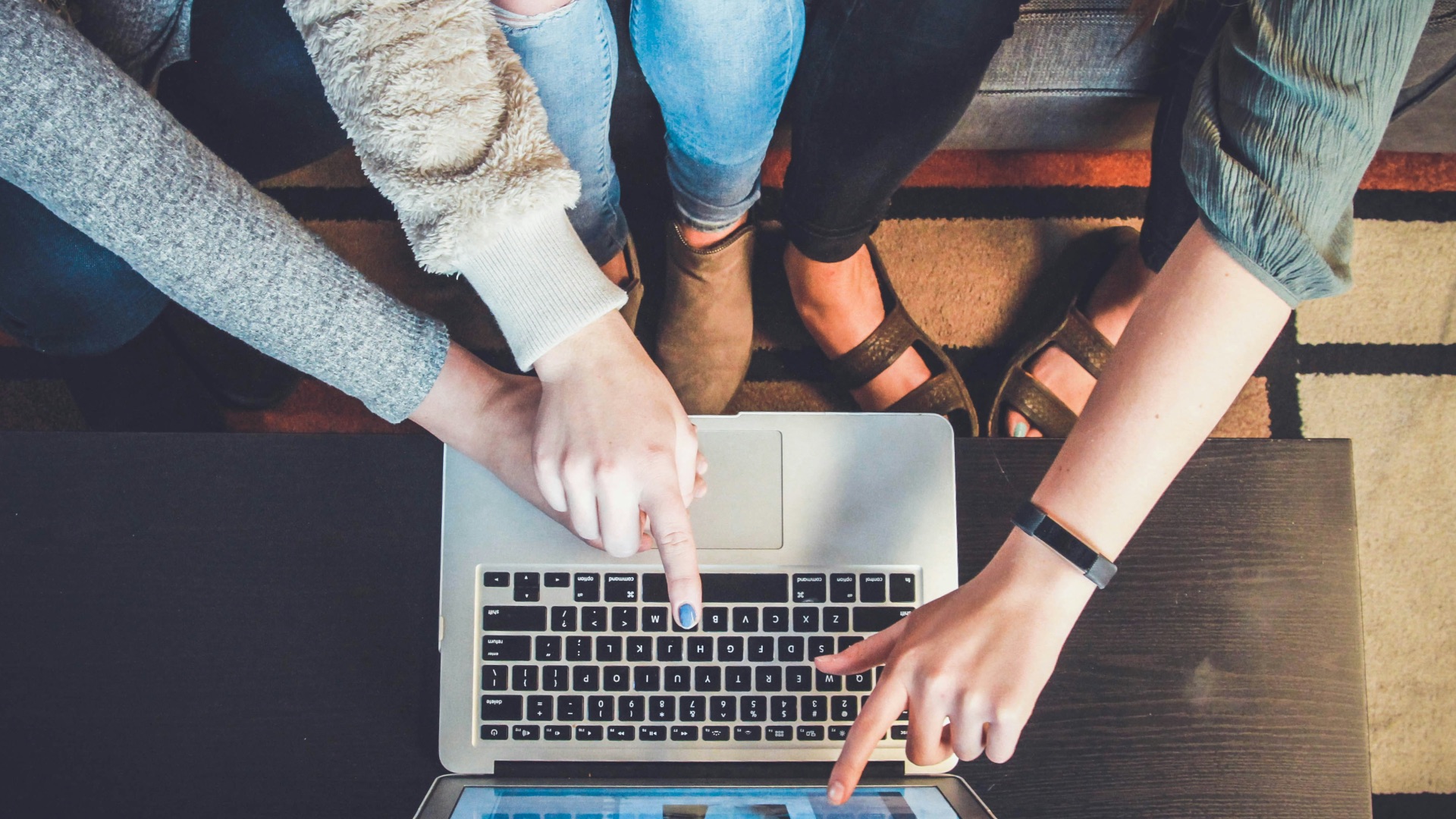 three person pointing the silver laptop computer
