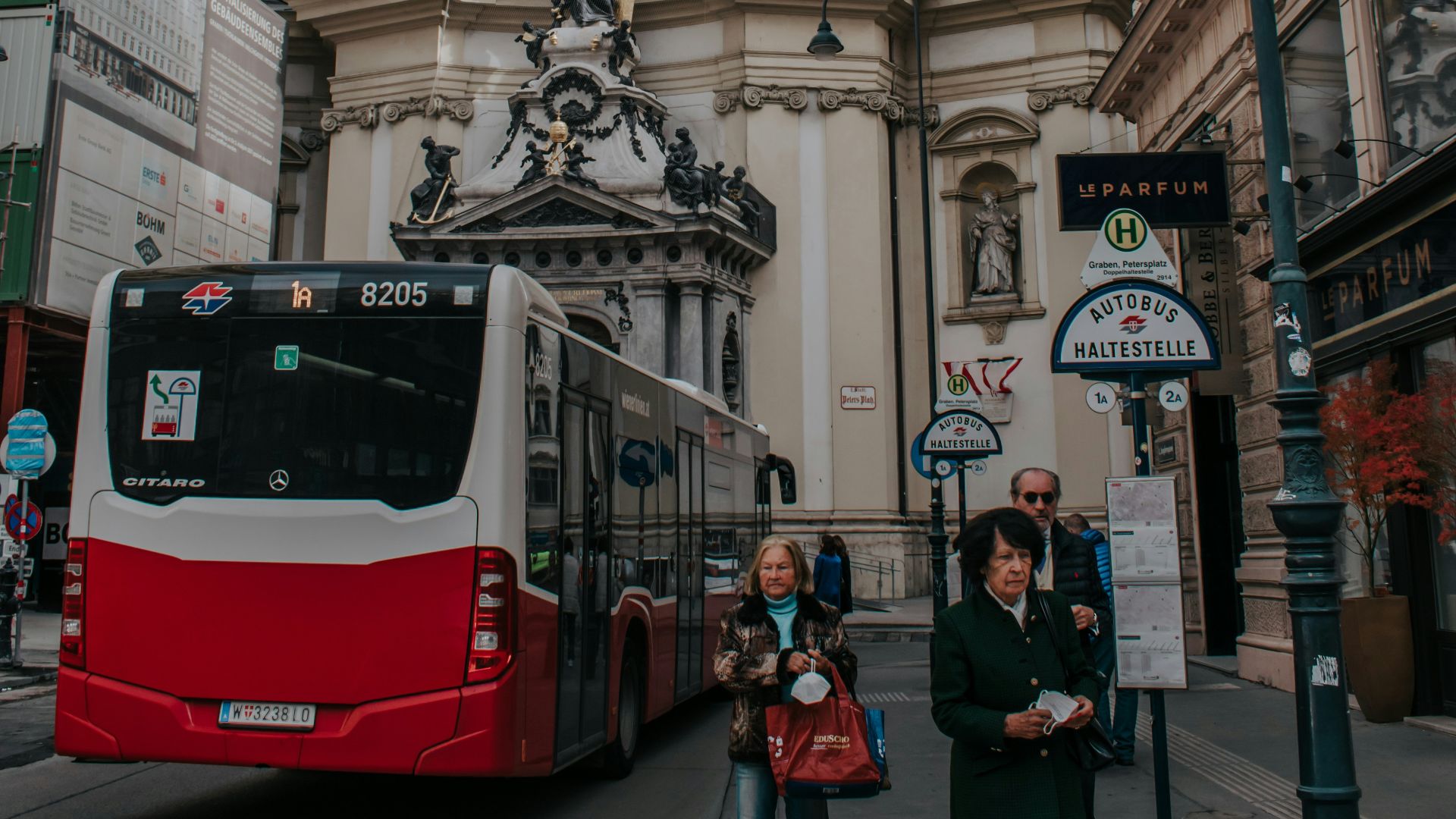 a red and white bus driving past a tall building
