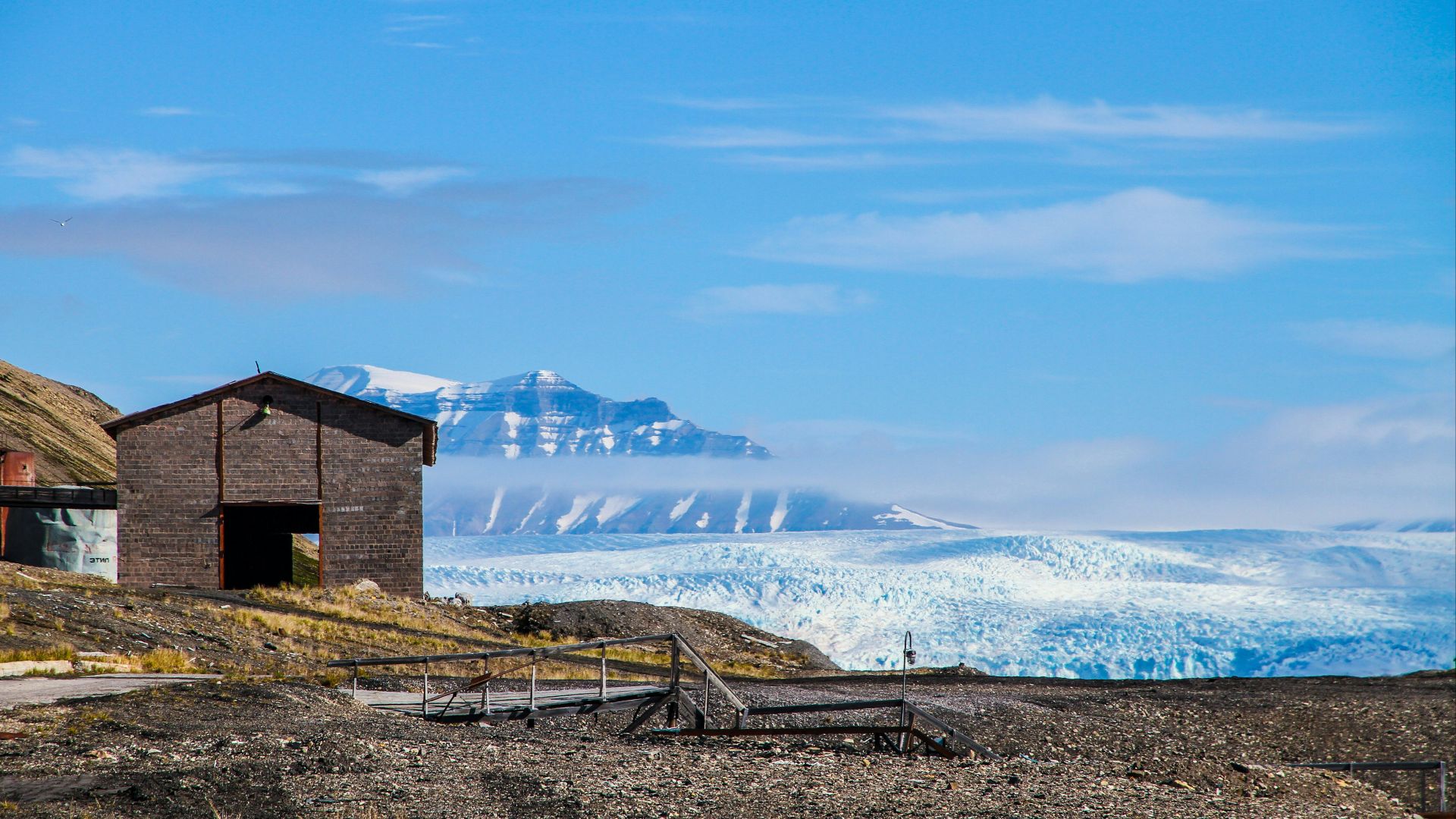 gray wooden shed overlooking snow-capped mountain