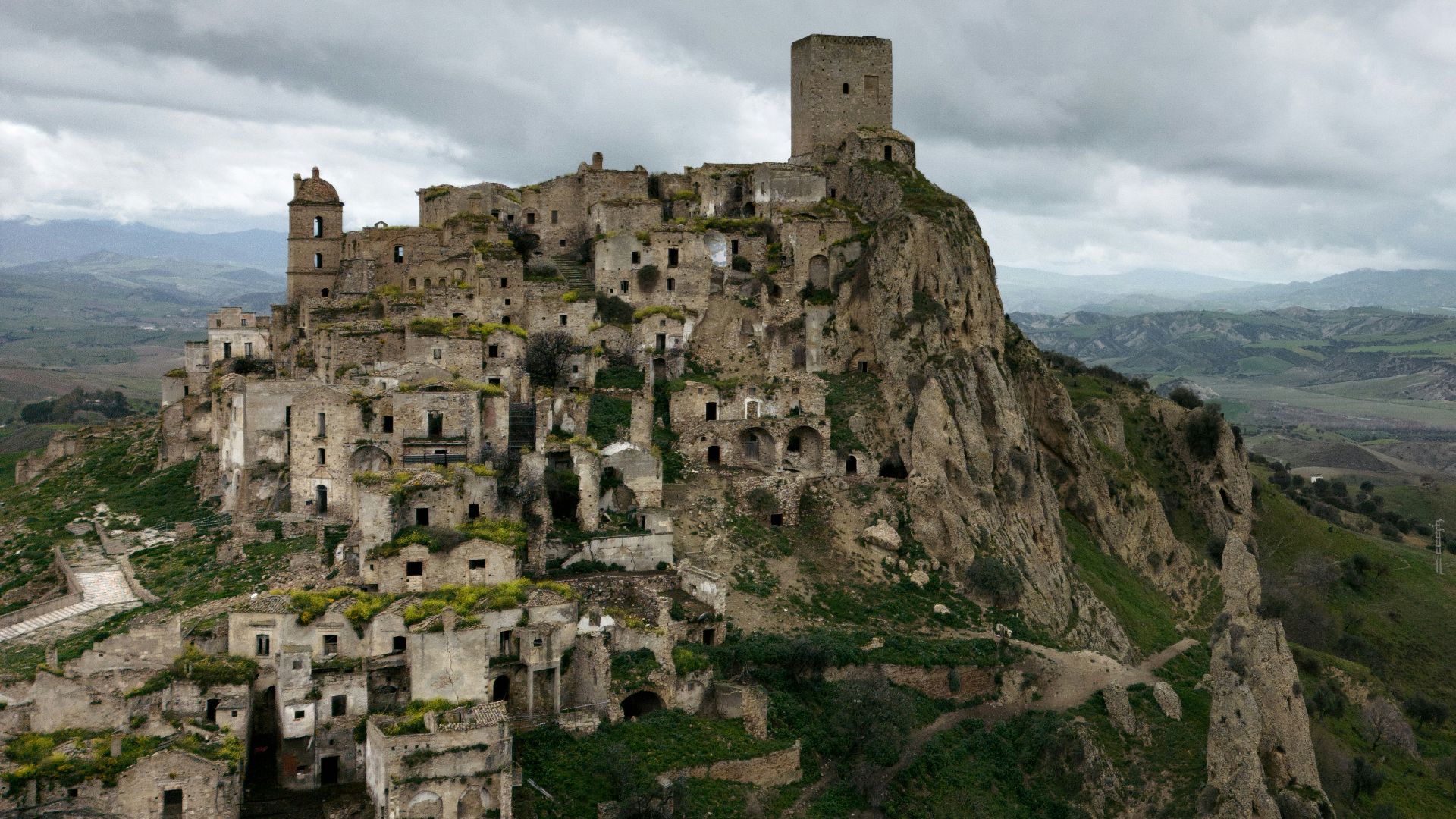 a castle perched on top of a mountain under a cloudy sky