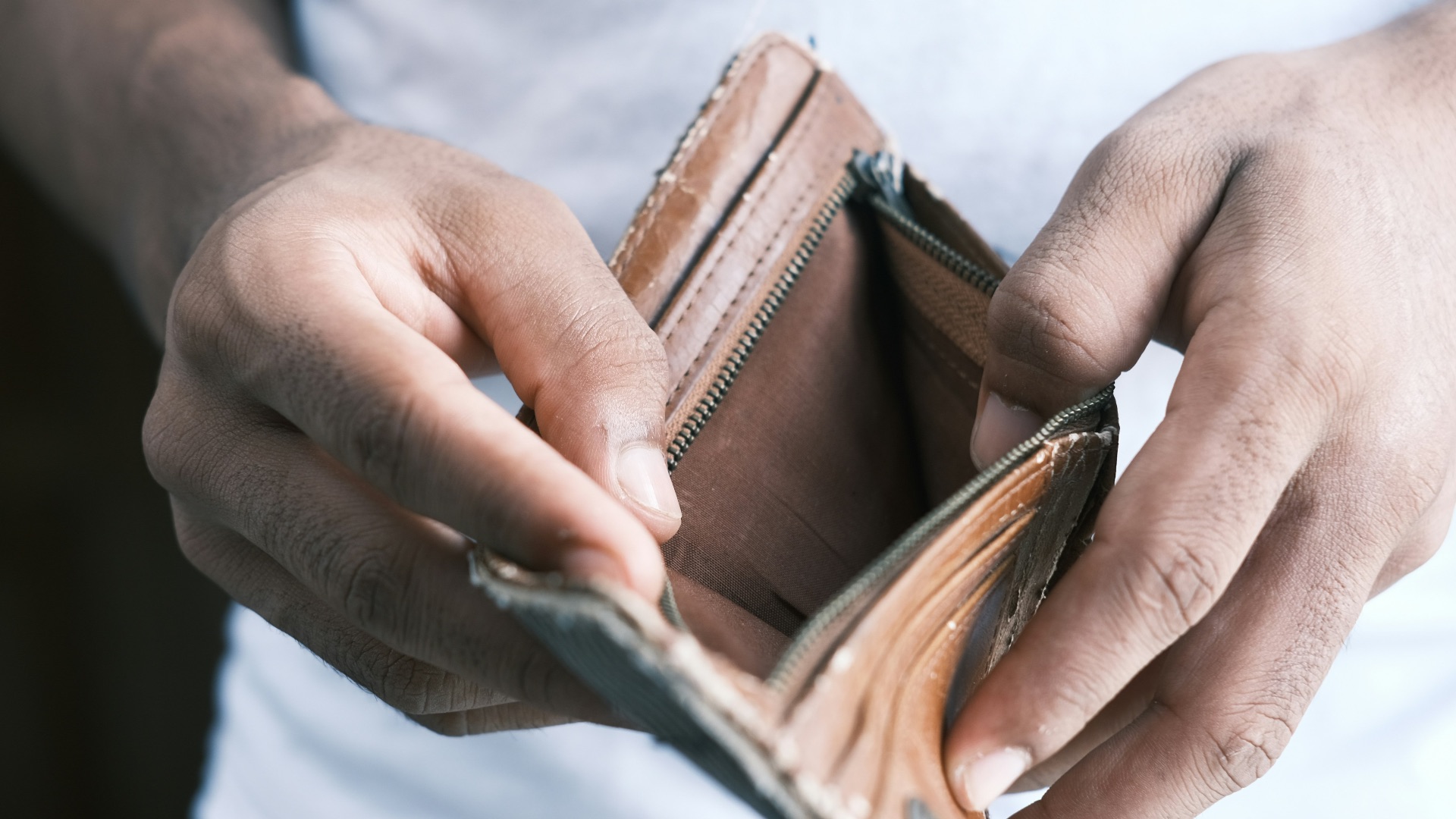 person holding brown leather bifold wallet