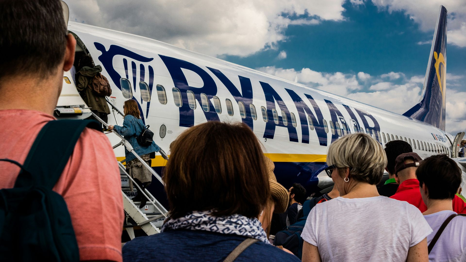people sitting on chair near blue and white airplane under white clouds during daytime