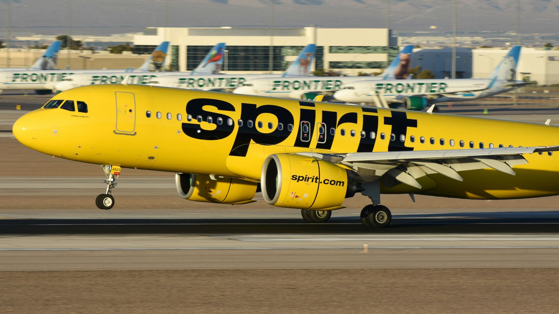 A yellow spirit airplane on the runway of an airport