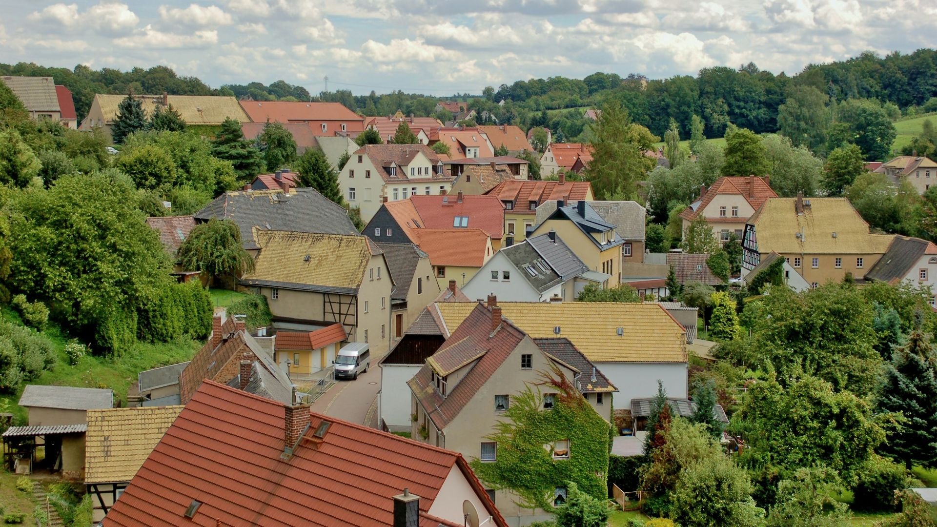 A picturesque village nestled among green trees and hills.
