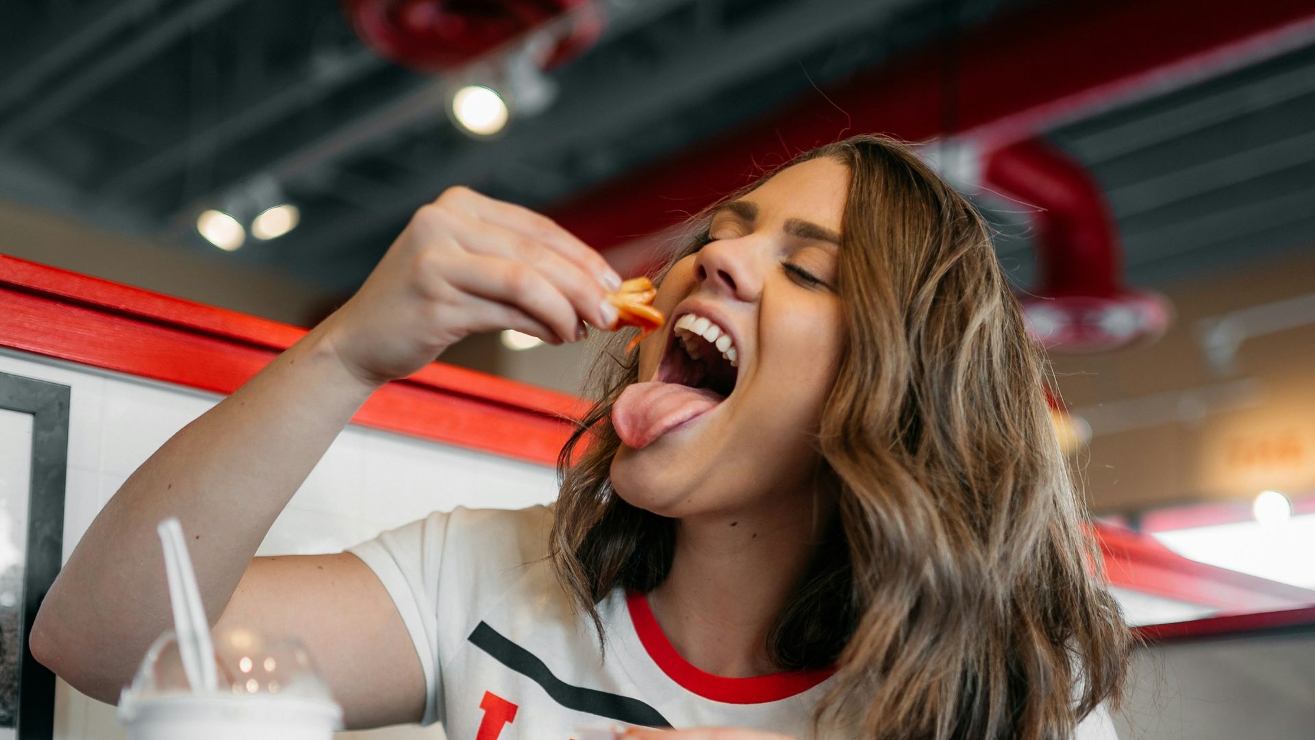 woman in white and red tank top eating