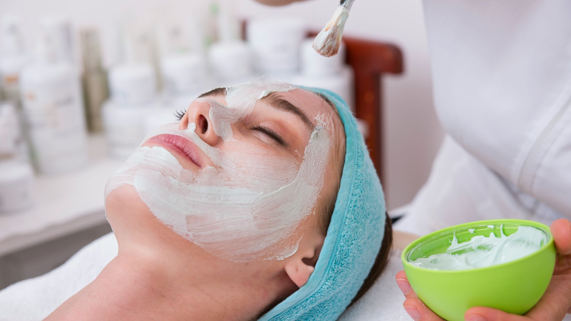 woman lying on blue towel with white cream on face