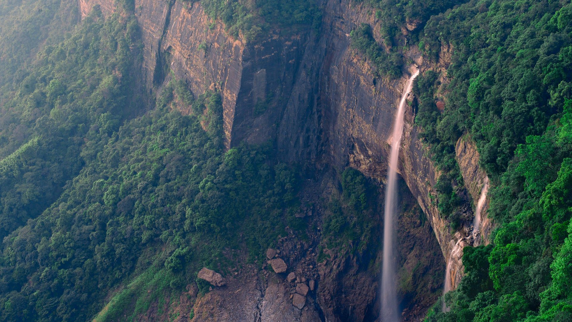 A waterfall in the middle of a lush green valley