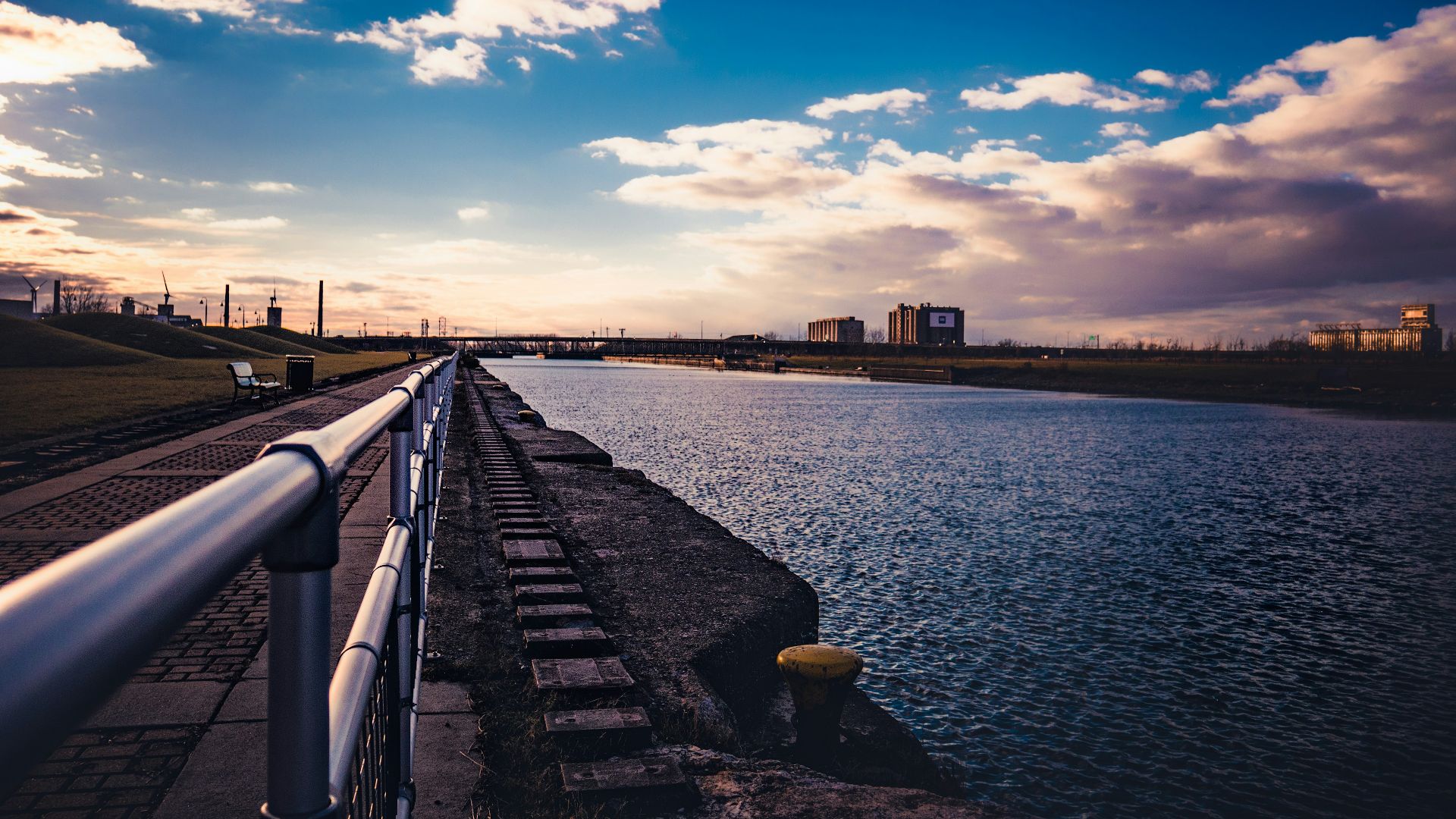 body of water near city buildings under blue and white sunny cloudy sky during daytime