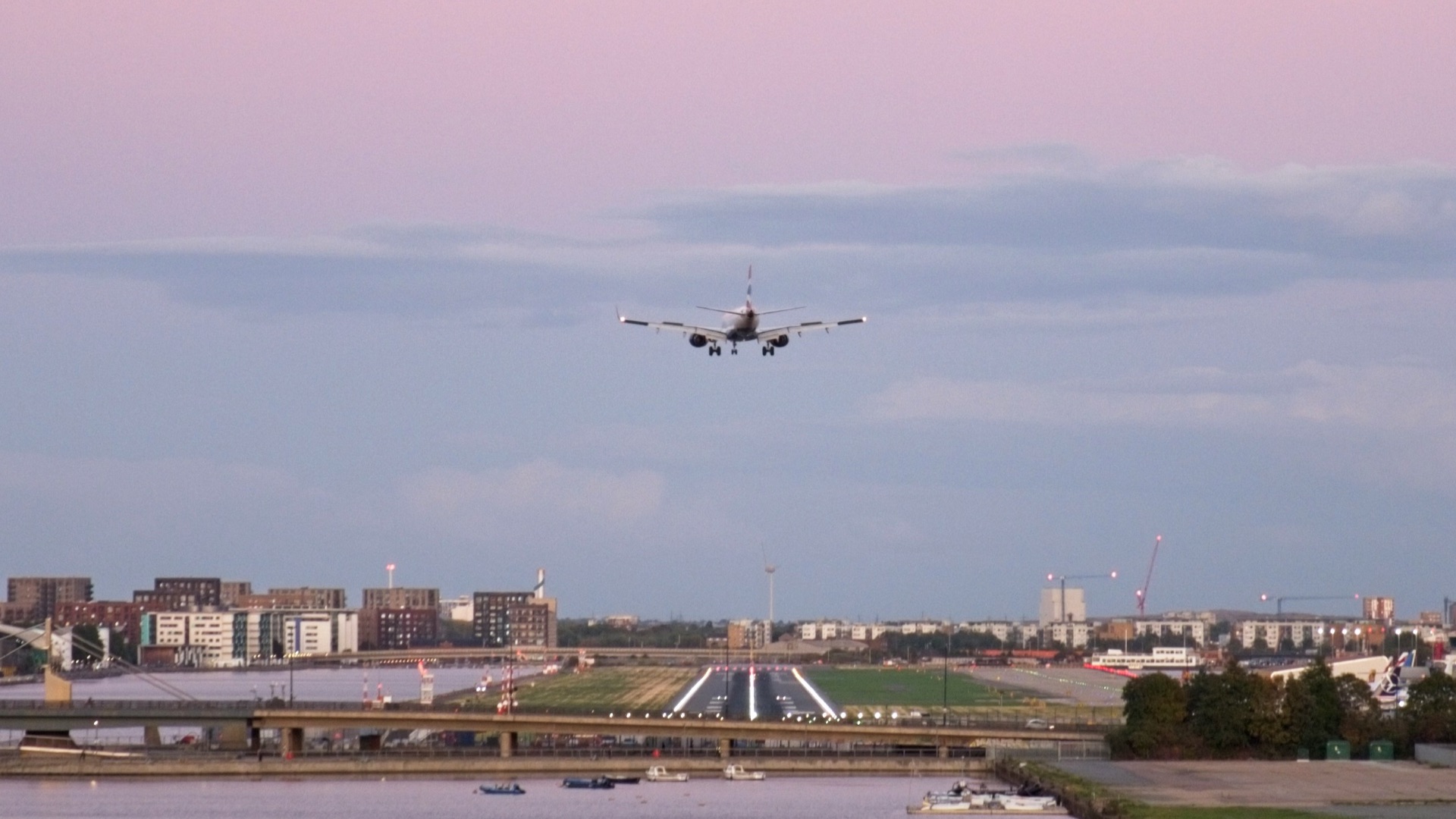 Airplane approaching runway over city and water