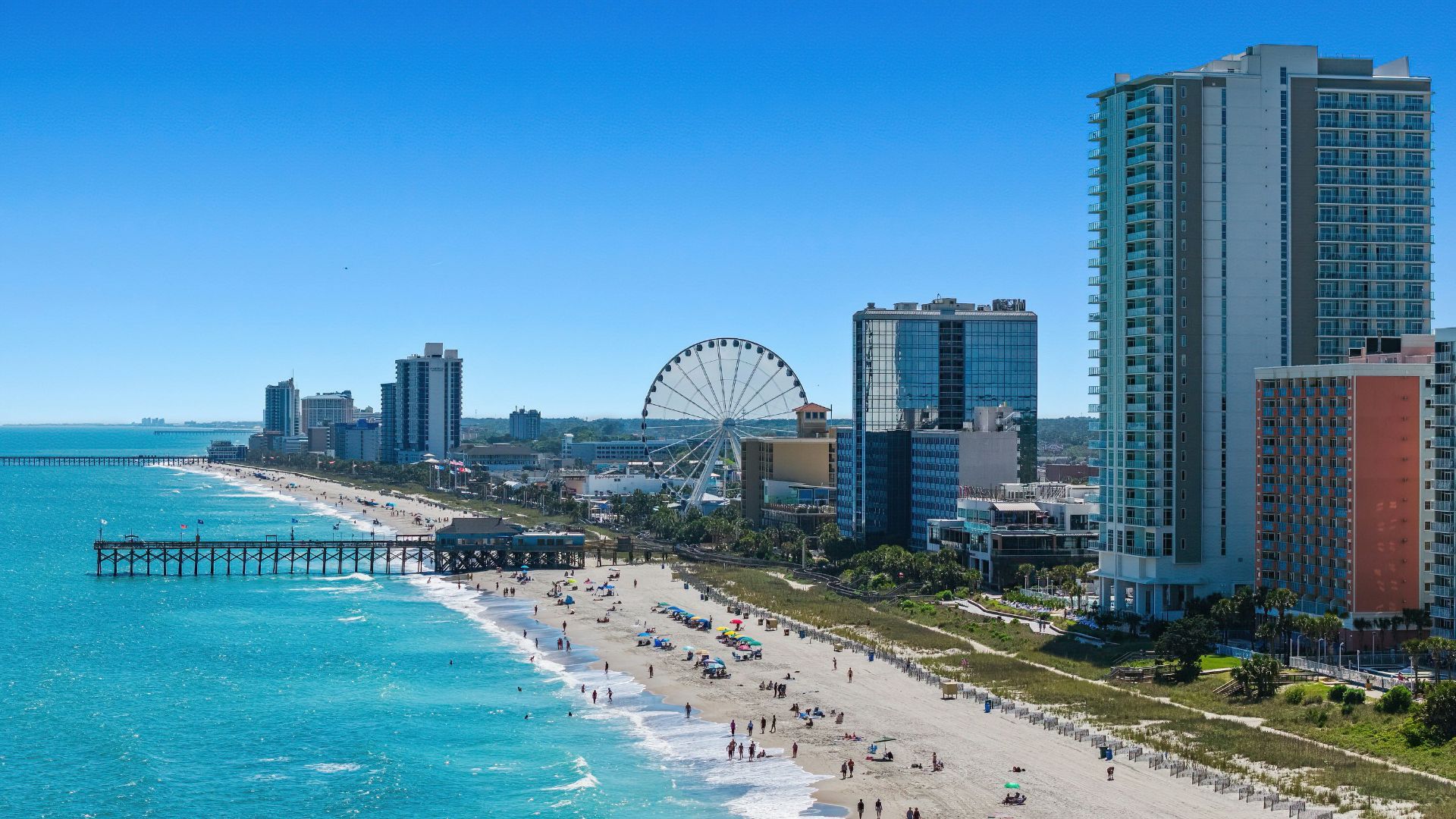 A view of a beach with a ferris wheel in the distance
