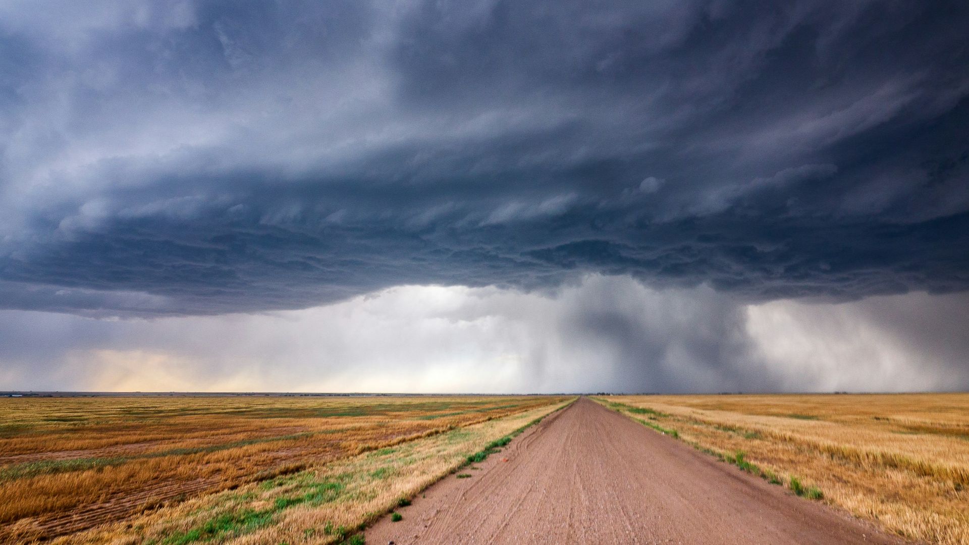brown dirt road under gray clouds