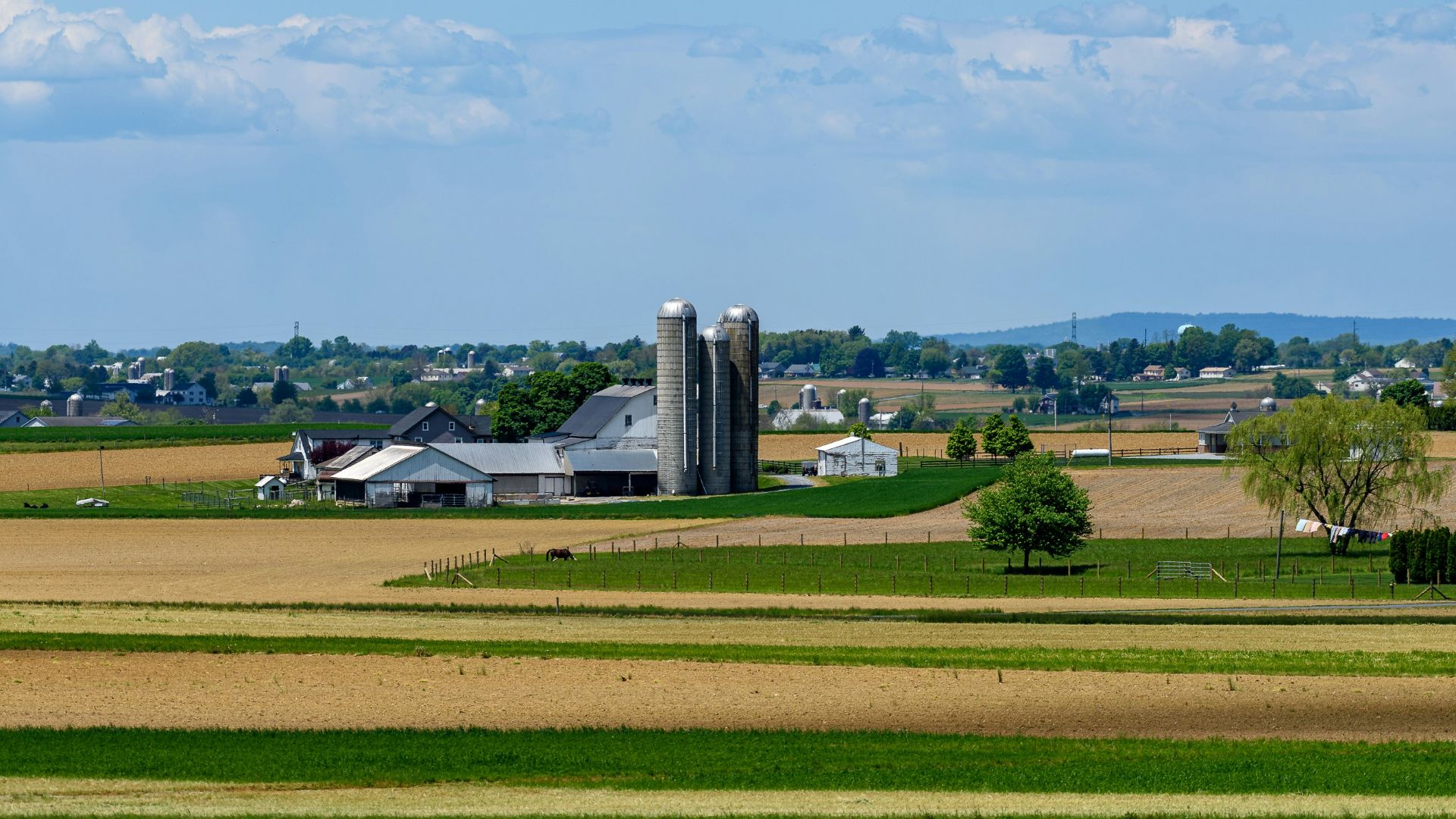 a farm with a grain silo in the distance