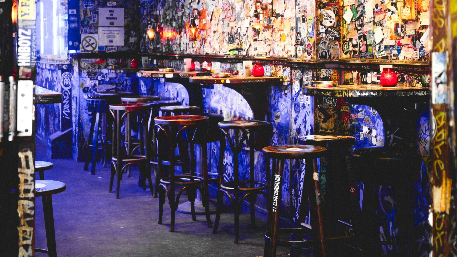 Dimly lit bar with graffiti-covered walls and stools