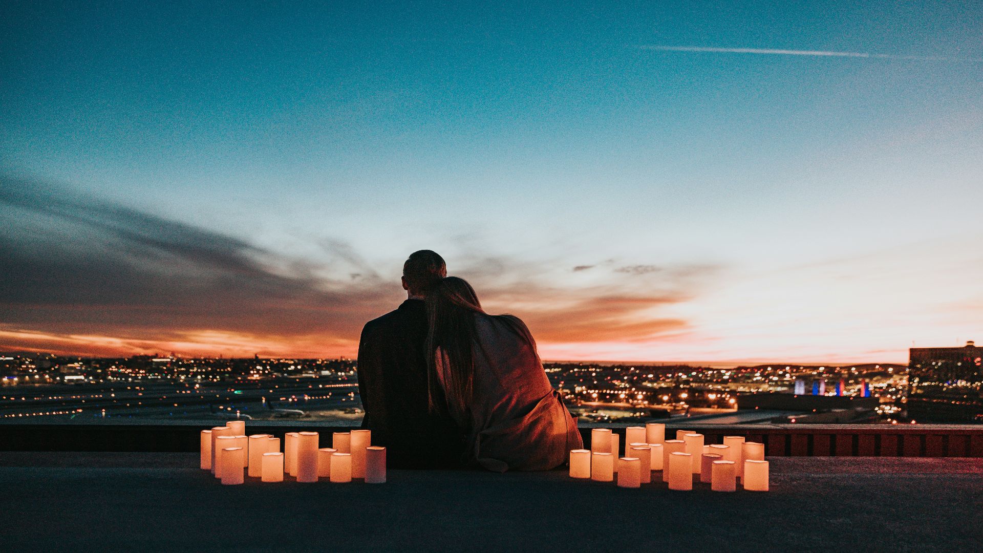 couple sitting on the field facing the city