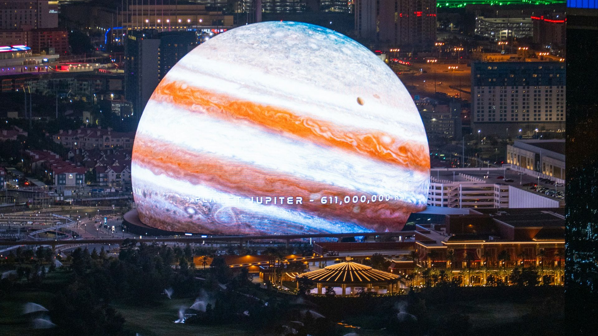 Jupiter projects over a cityscape at night.
