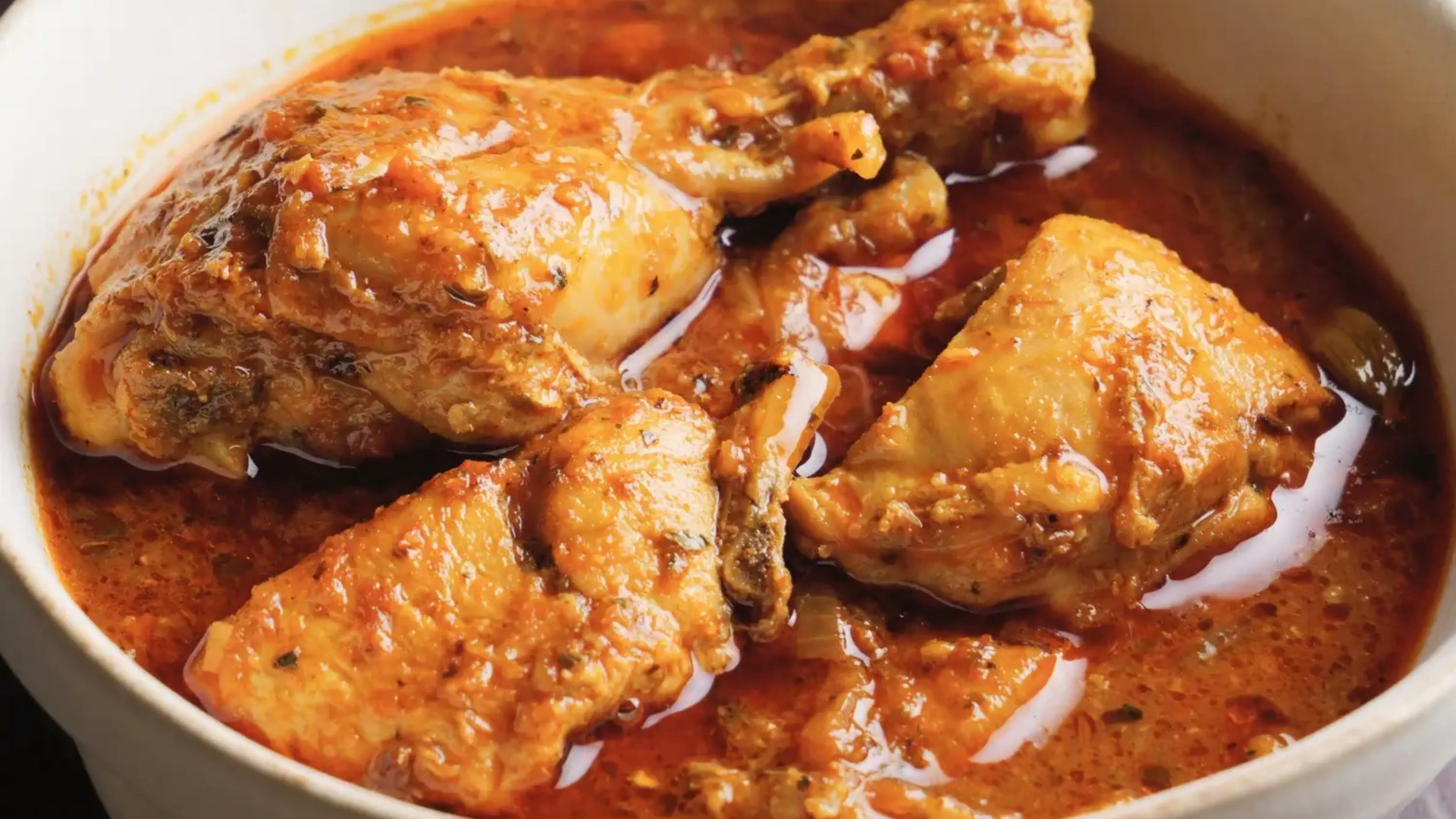 Chicken curry in a white bowl with sauce.