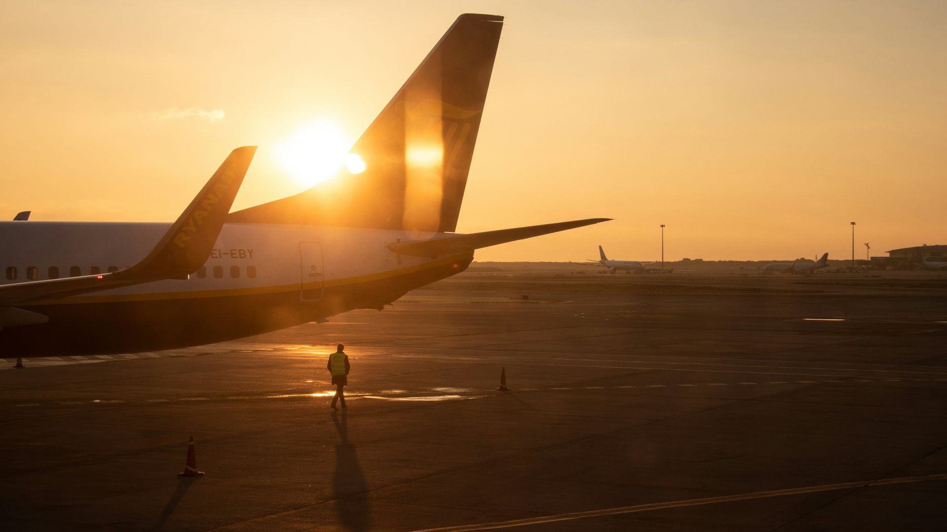 man walking under jet plane at the tarmac during sunset
