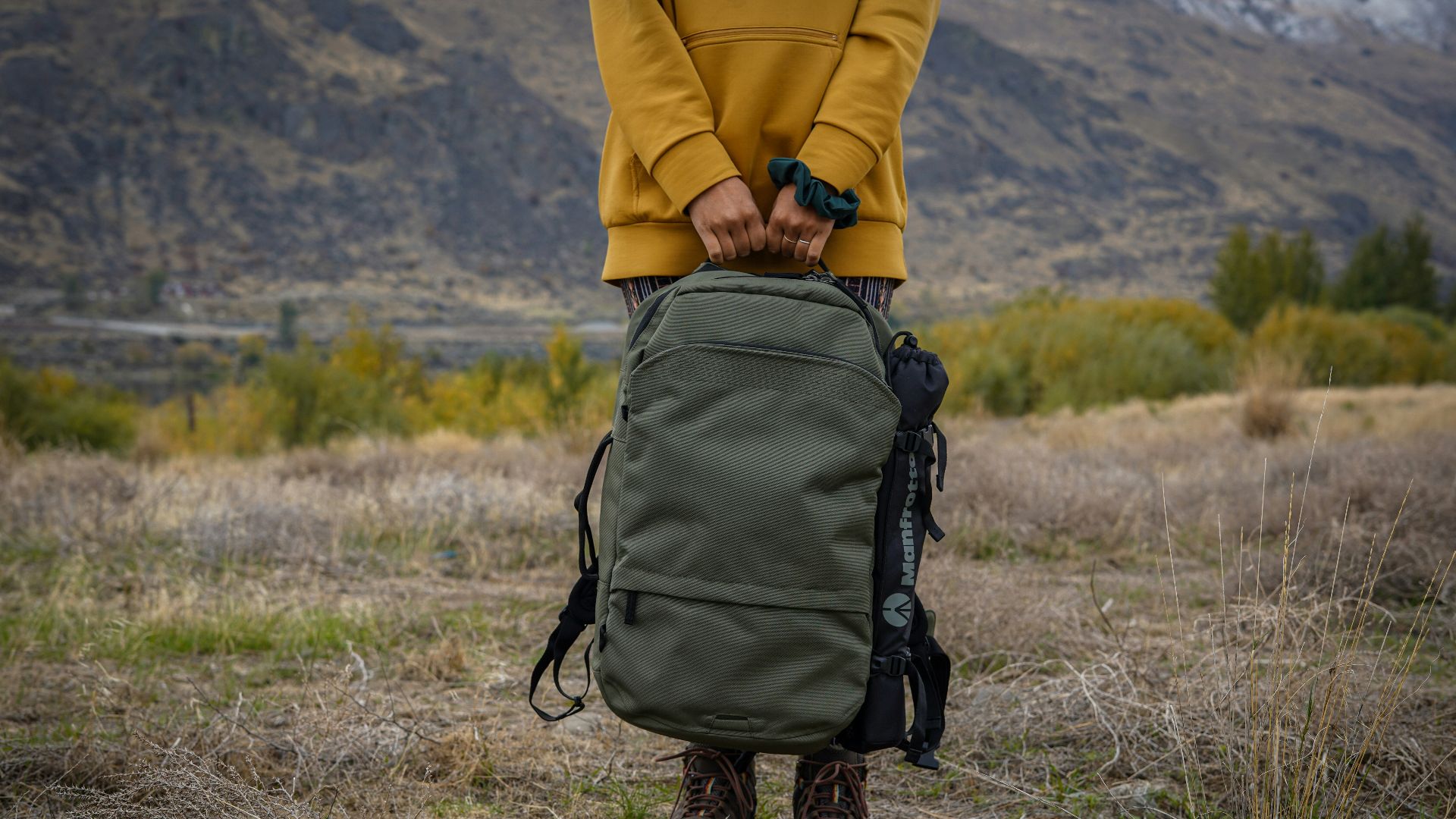 person in yellow jacket and black backpack walking on brown grass field during daytime