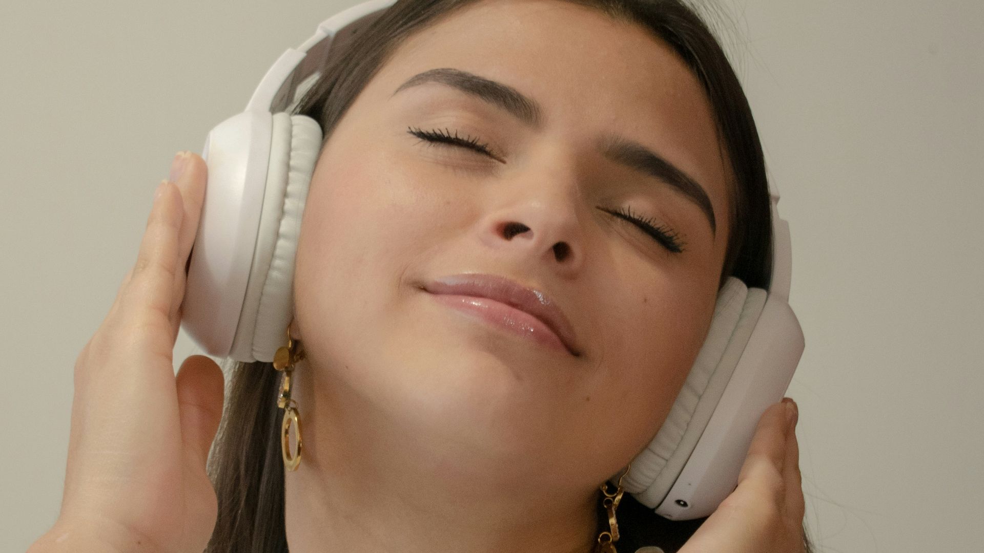 a woman with her eyes closed holding a phone to her ear