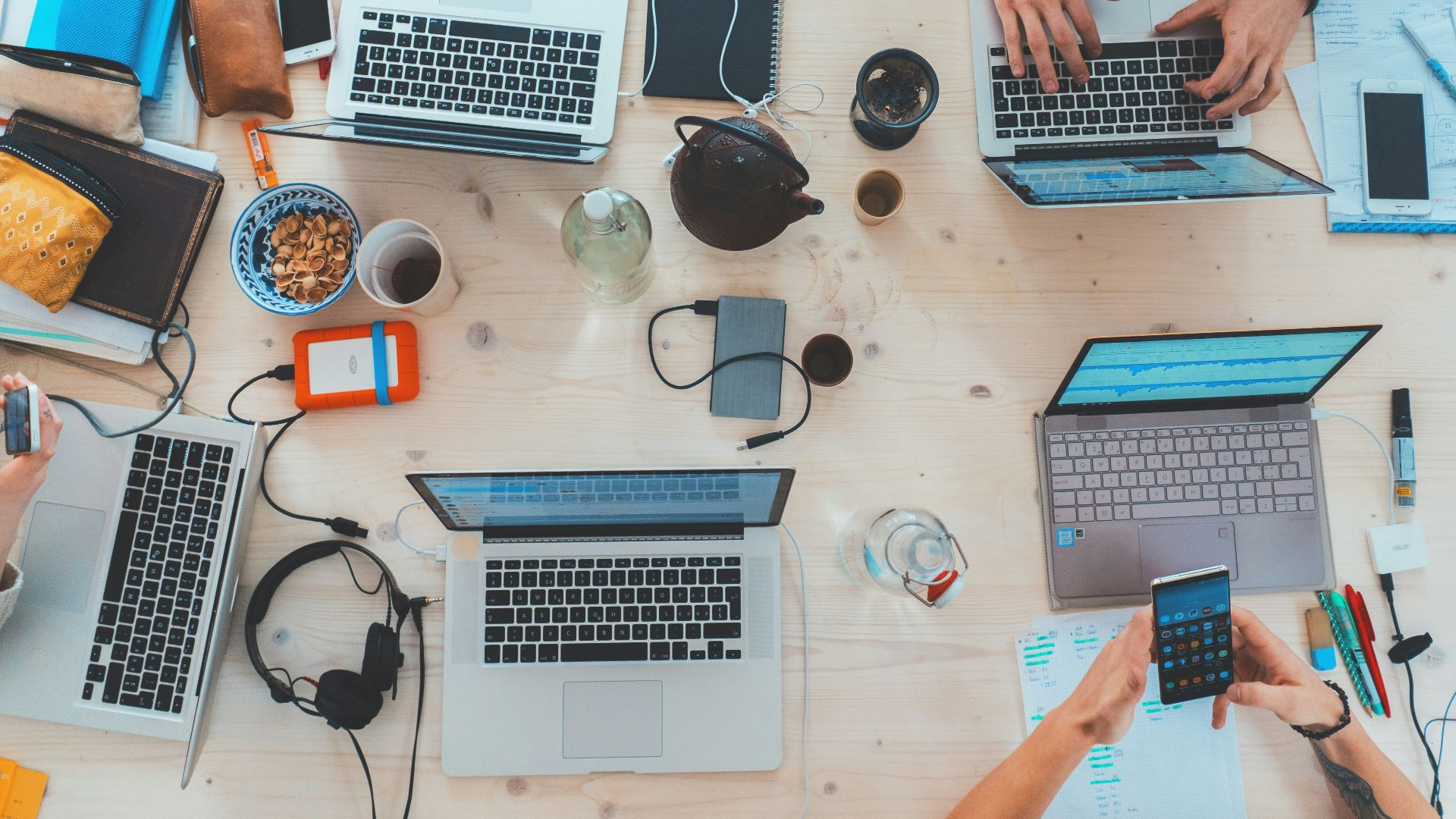 people sitting down near table with assorted laptop computers