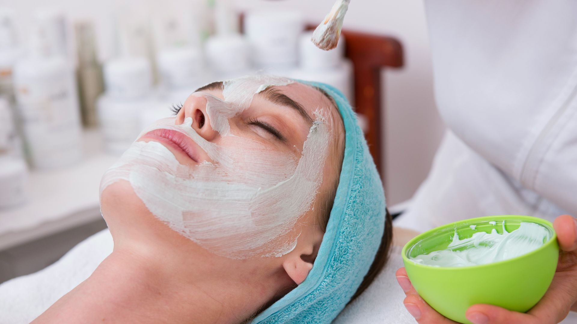 woman lying on blue towel with white cream on face