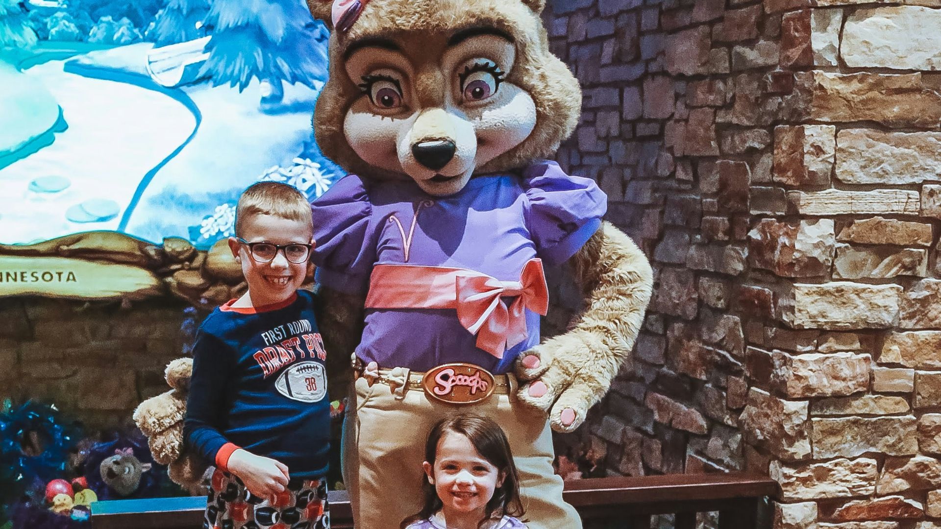 a couple of kids standing next to a stuffed animal