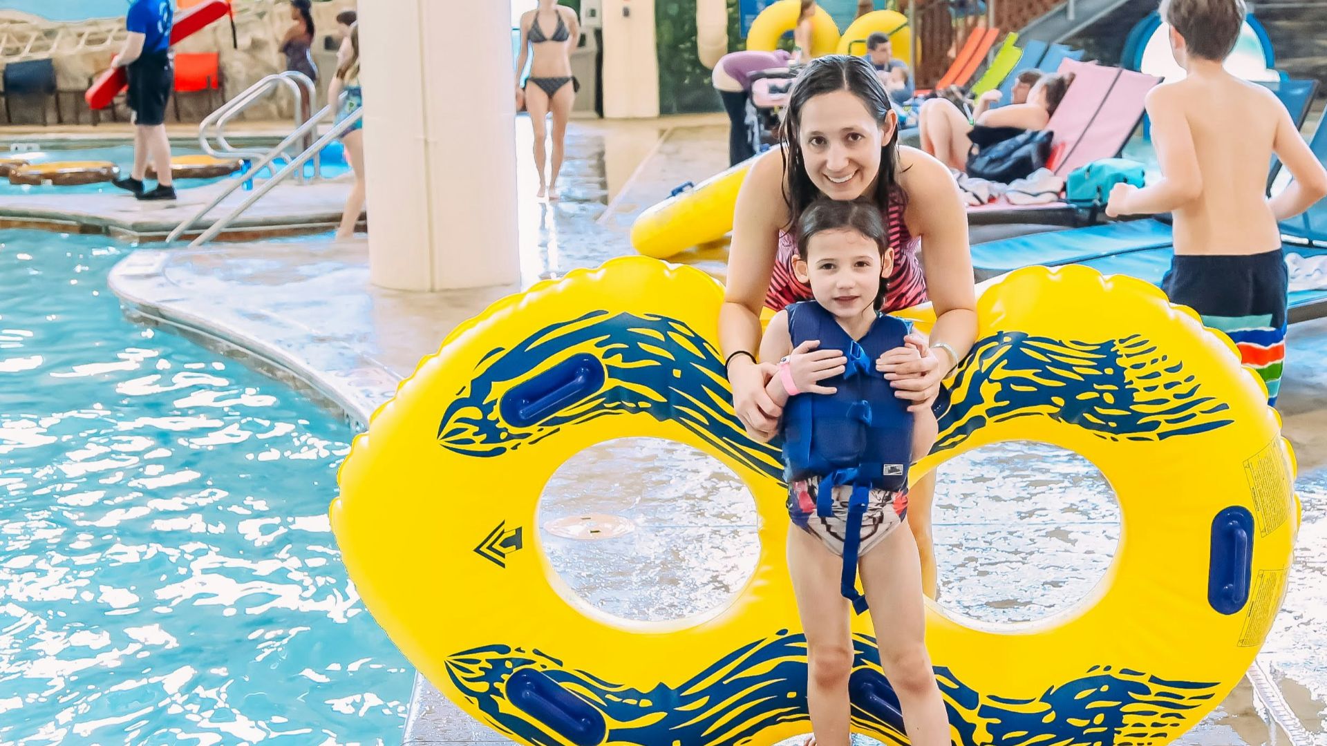 a woman holding a child on a raft in a pool