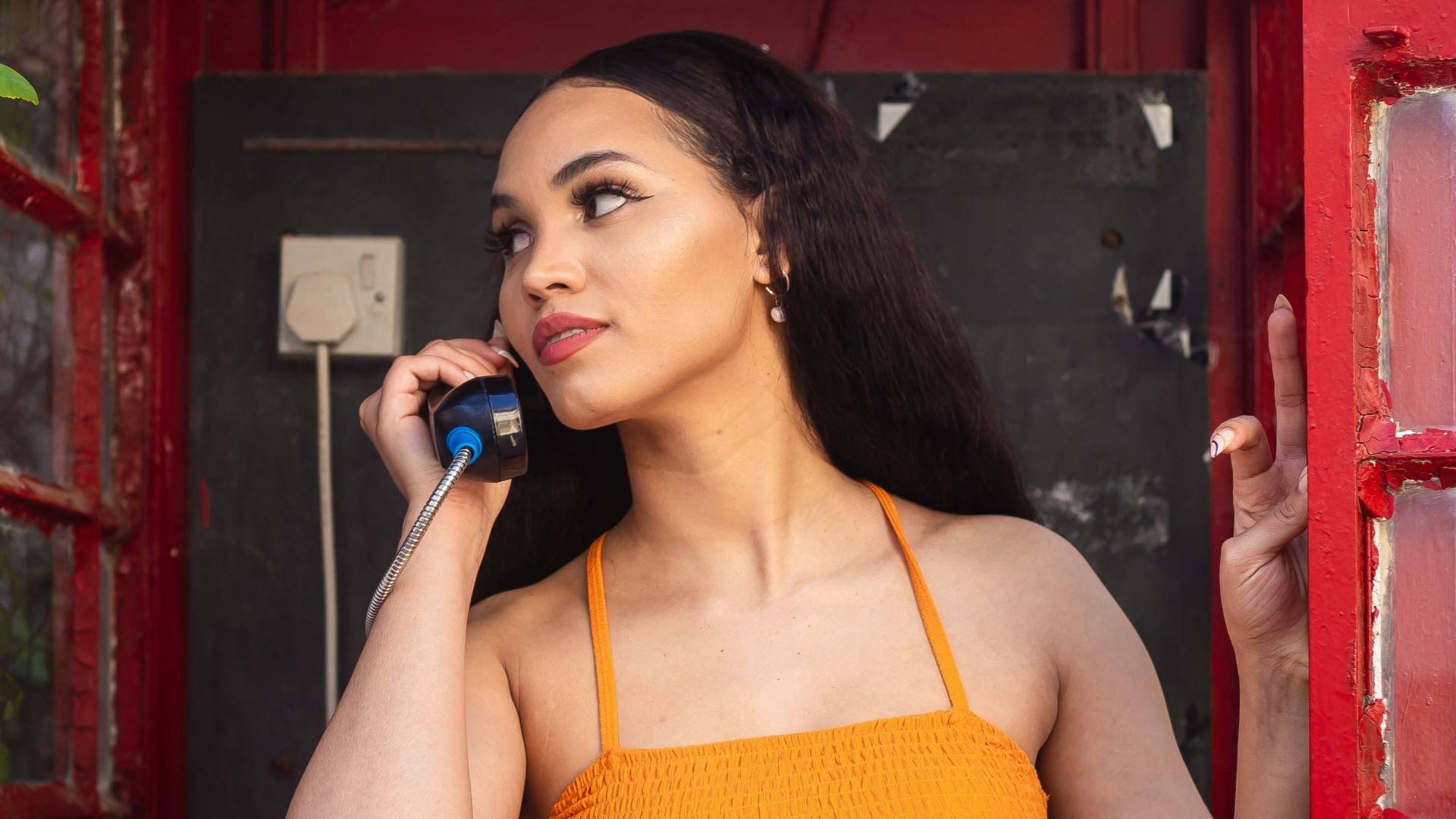 a person in an orange dress talks on a cell phone