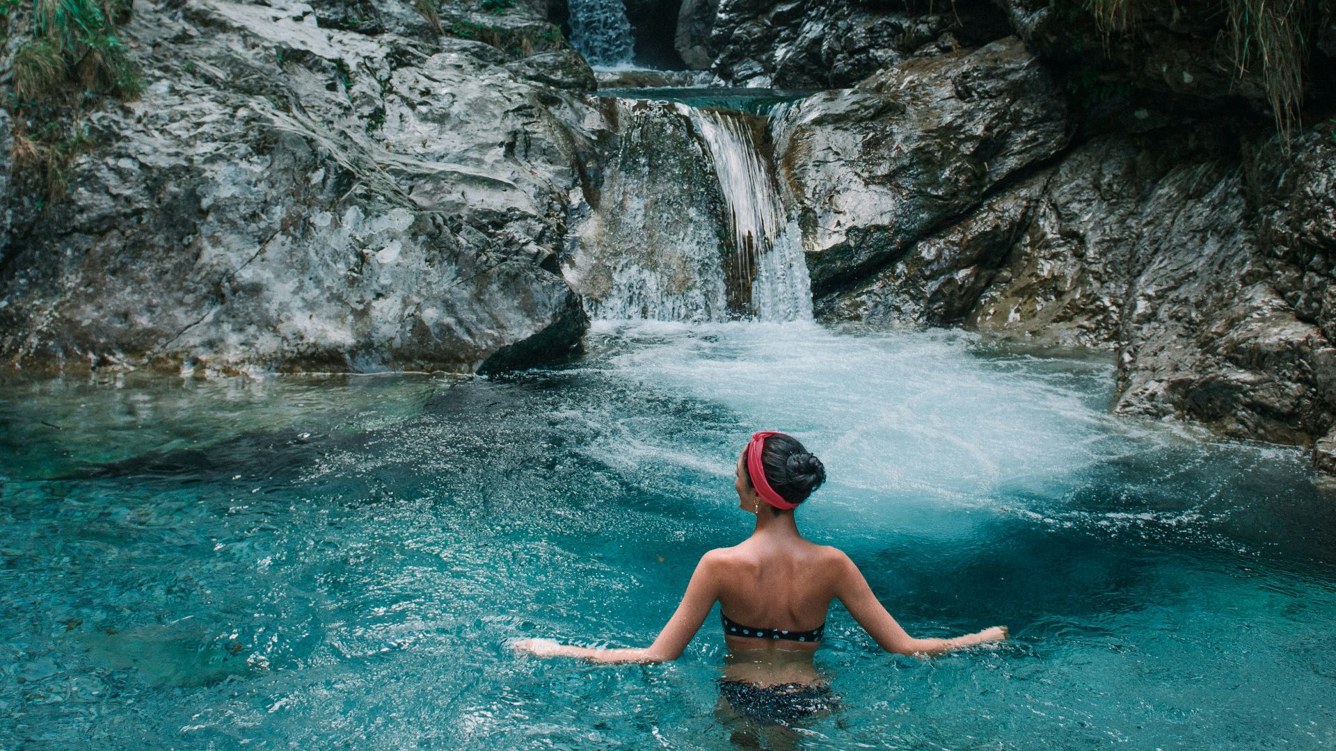woman on body of water near waterfall during daytime