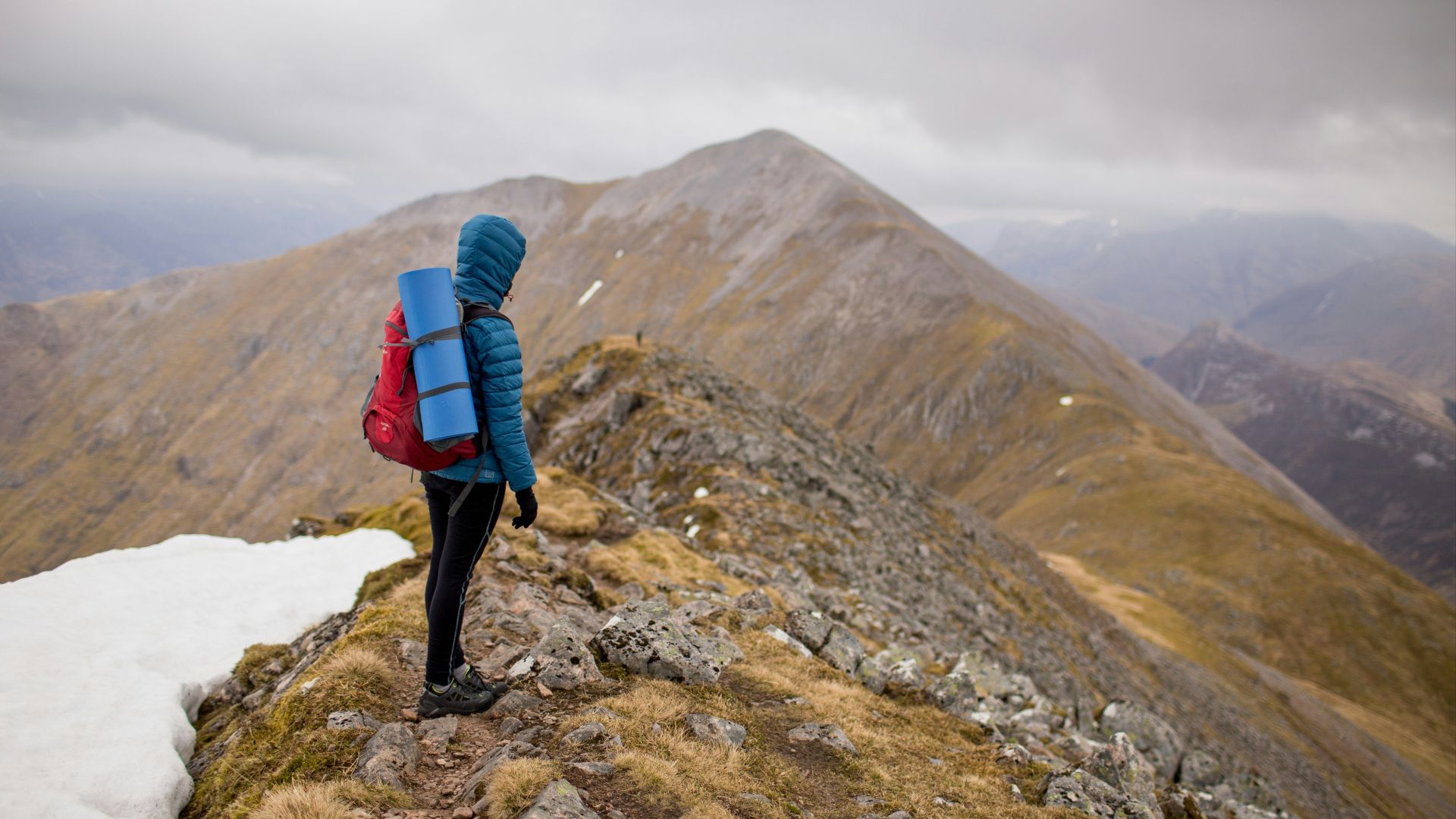 person at peak of mountain carrying red backpack