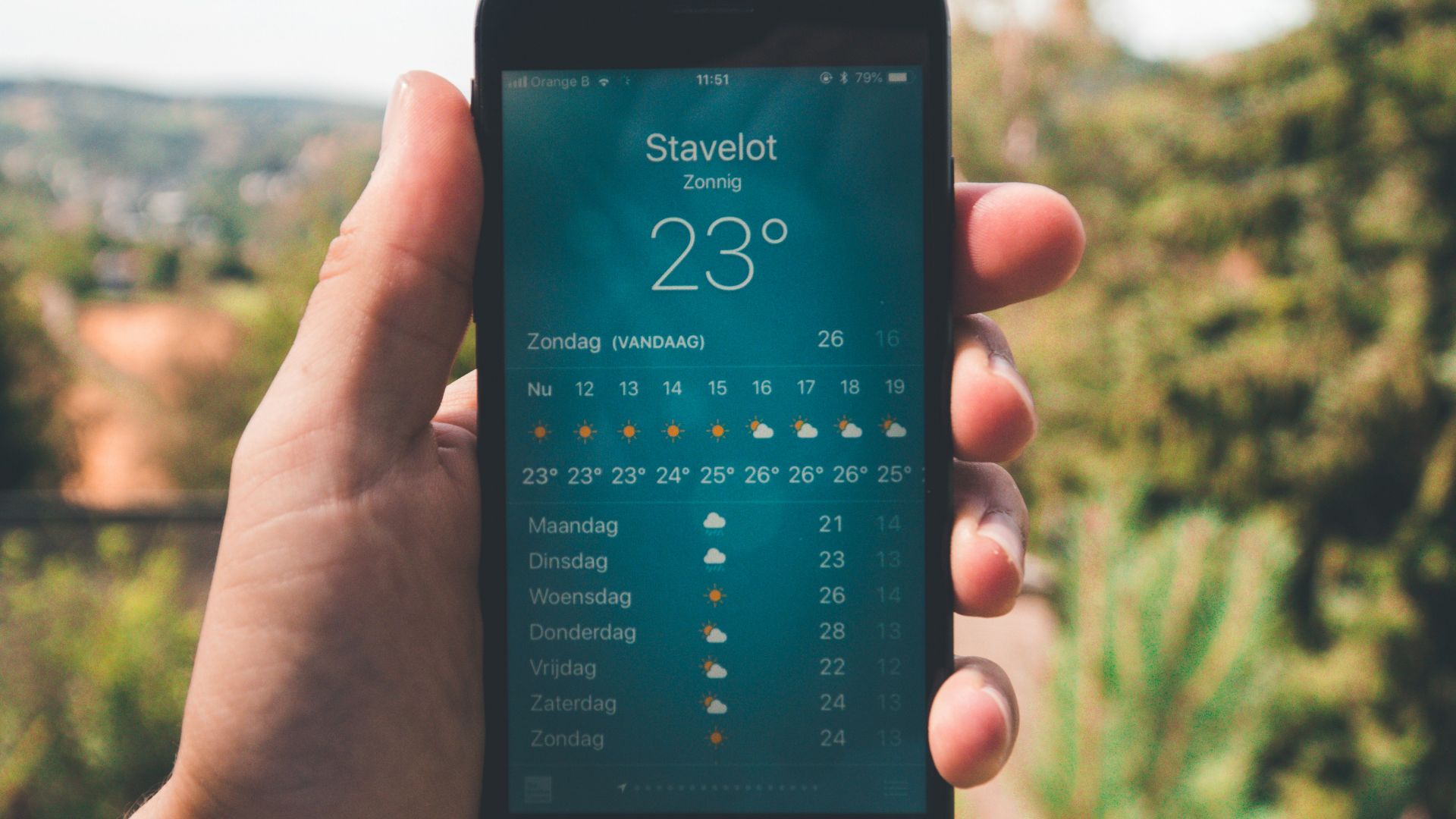person holding iPhone 7 displaying 23 degree celcius