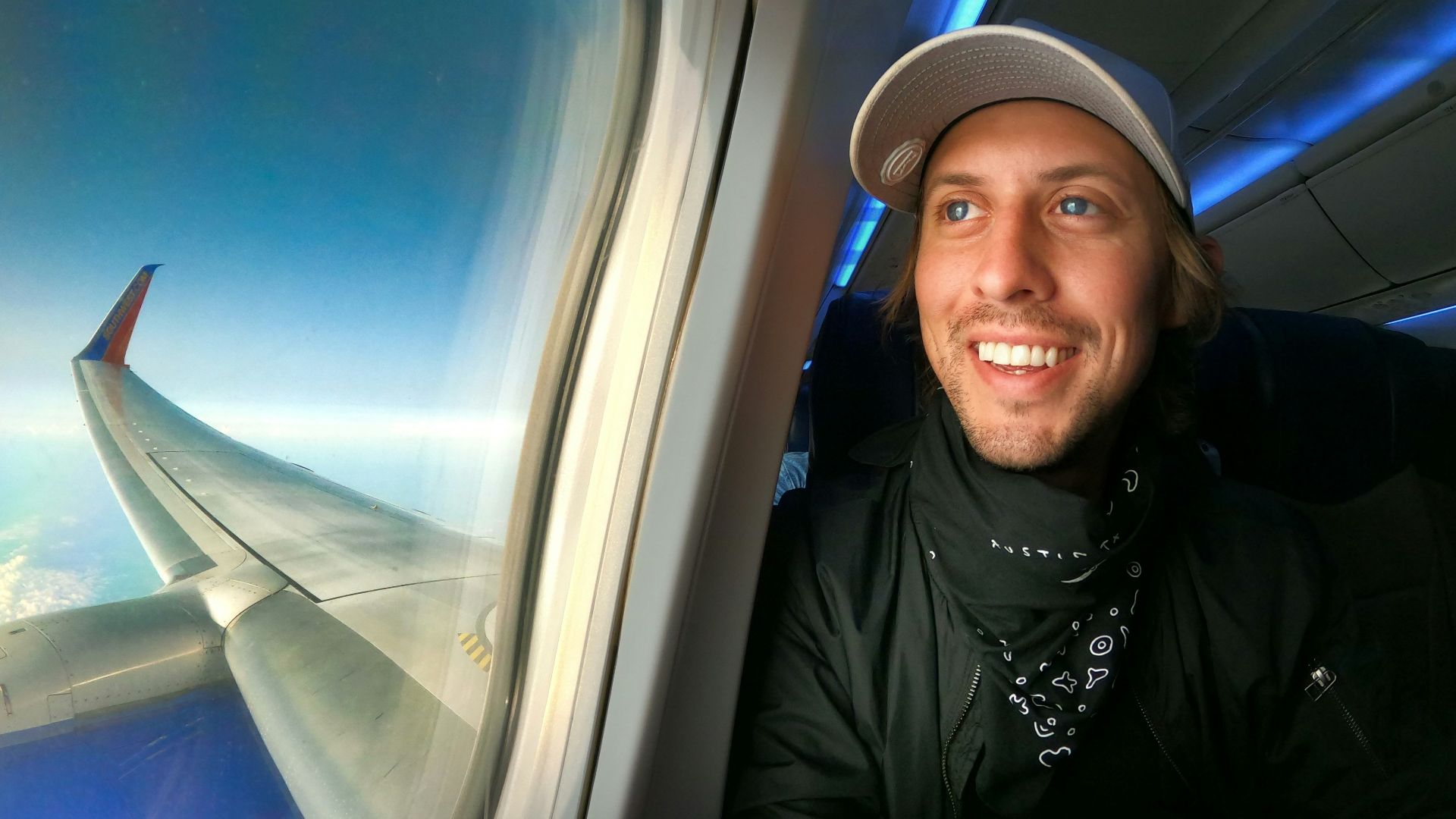 smiling woman in black jacket wearing blue cap